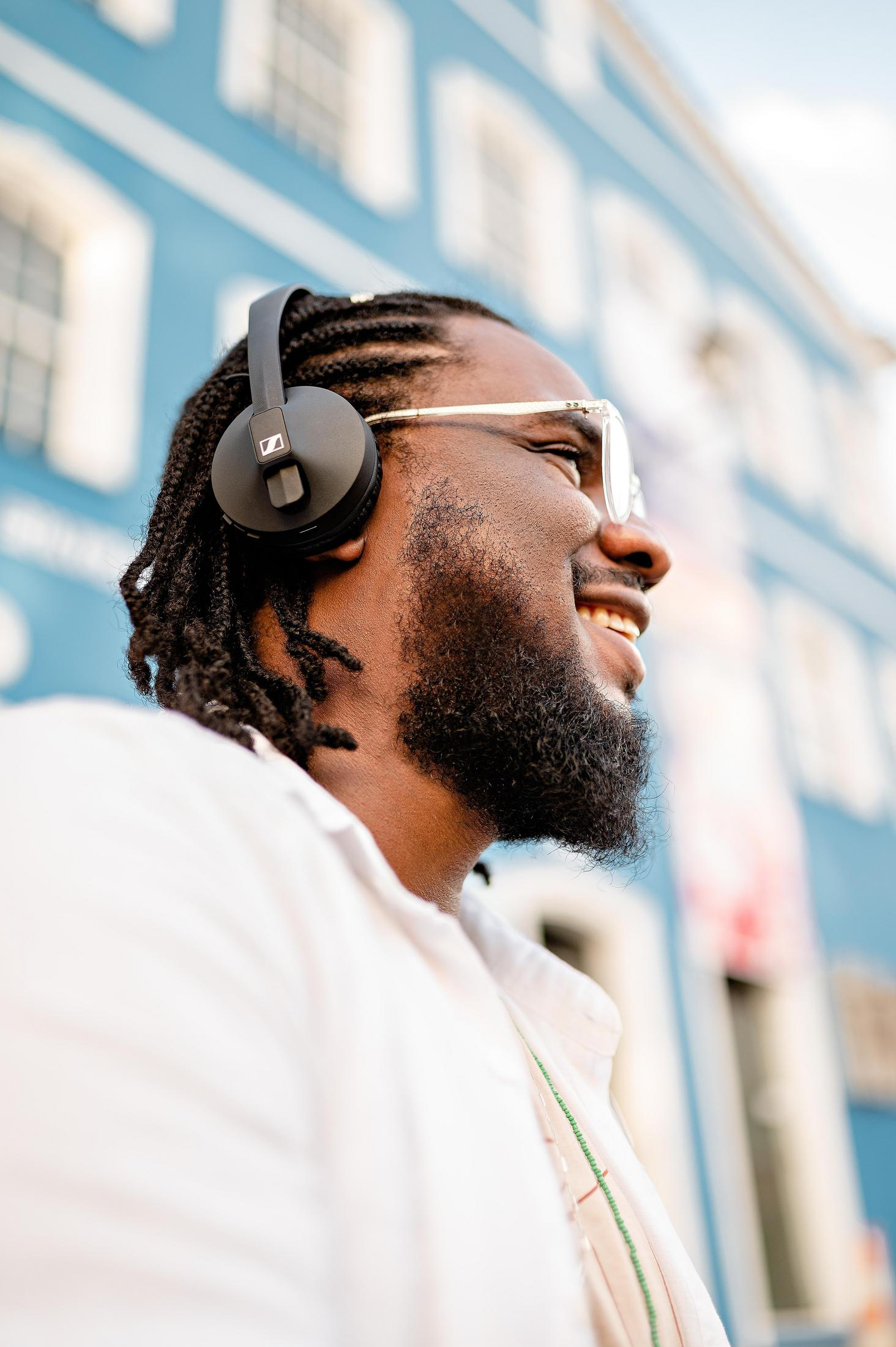Homme avec un casque souriant, devant un bâtiment bleu.