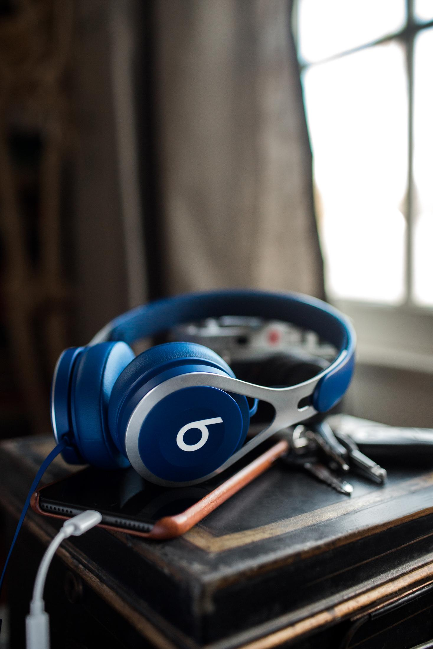 Blaue Beats-Kopfhörer auf einem Tisch, mit Schlüsseln und Telefon.