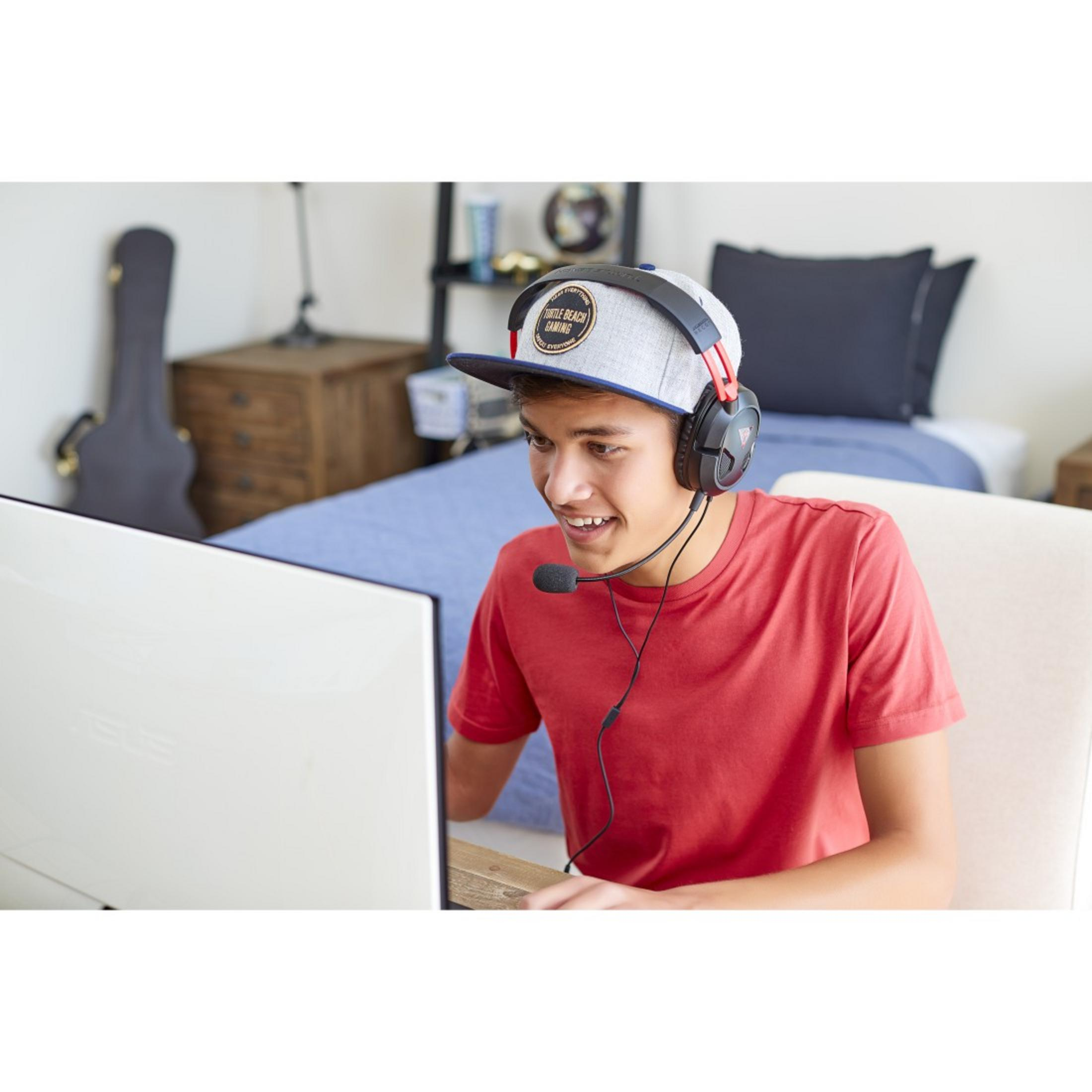 Adolescent jouant à un jeu vidéo dans une pièce, portant un casque et une casquette.