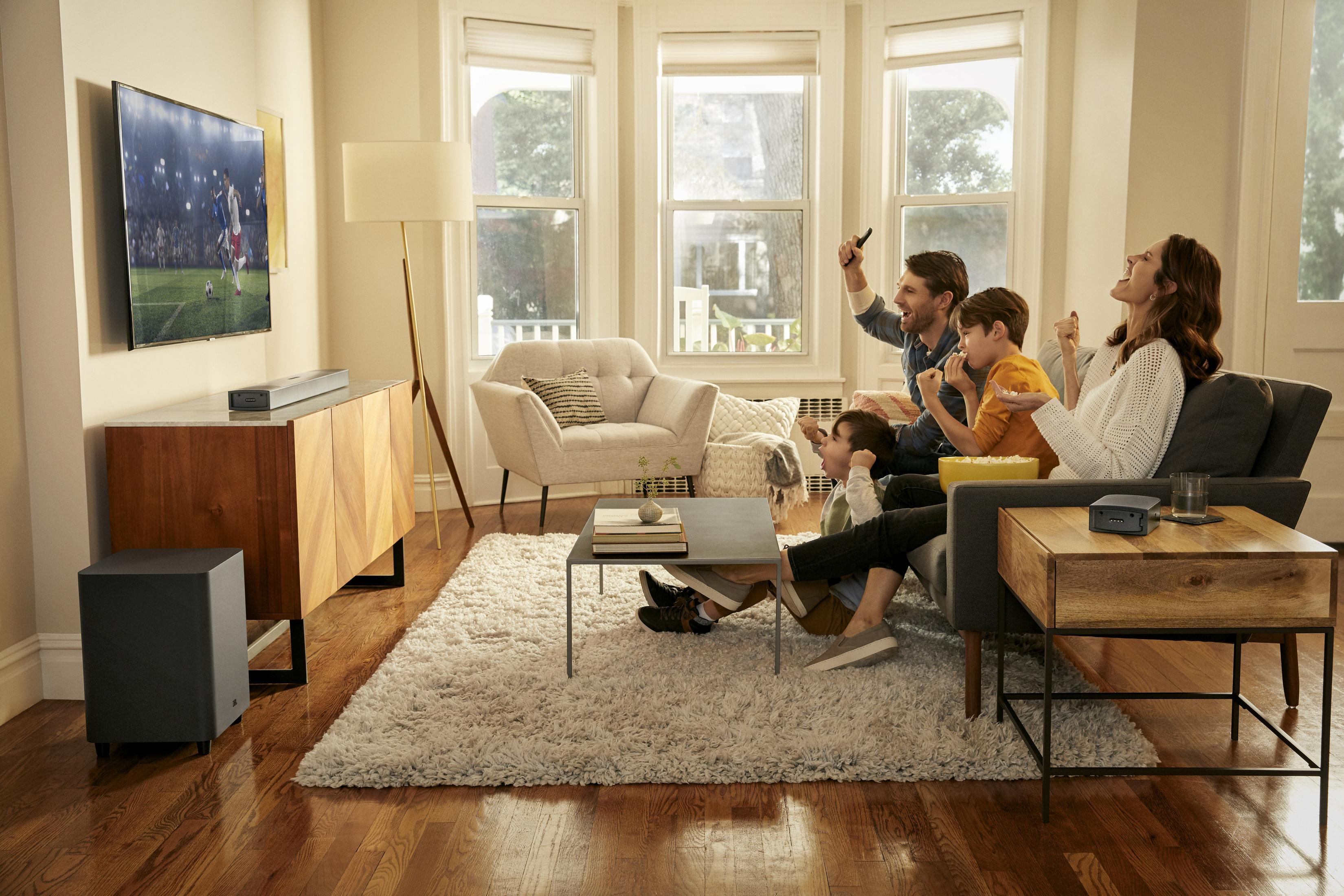 Familia viendo la televisión en la sala de estar, TV moderna, barra de sonido, subwoofer.