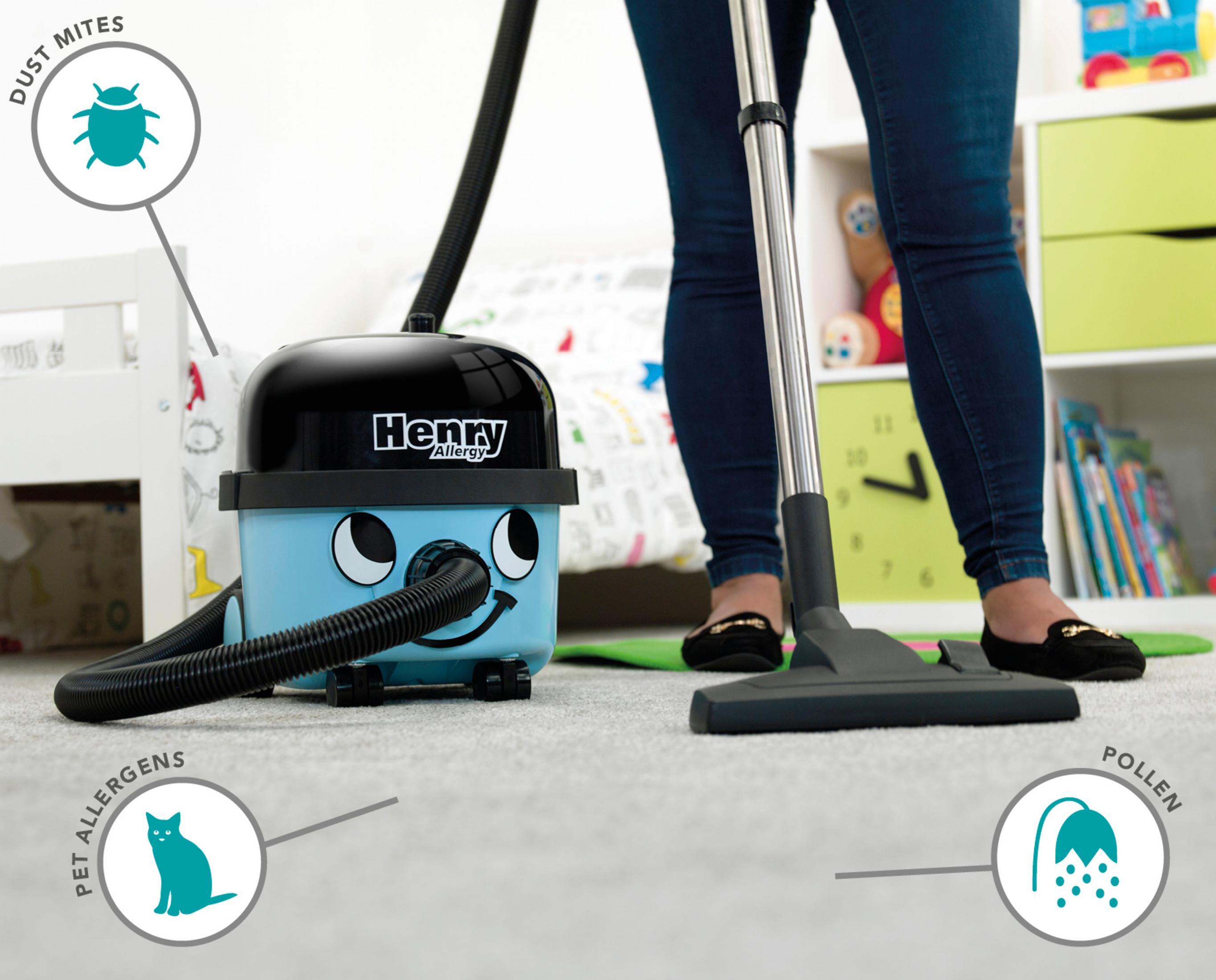 Niebieski odkurzacz z uśmiechniętą twarzą, obok dywanu z tekstem i ikonami.