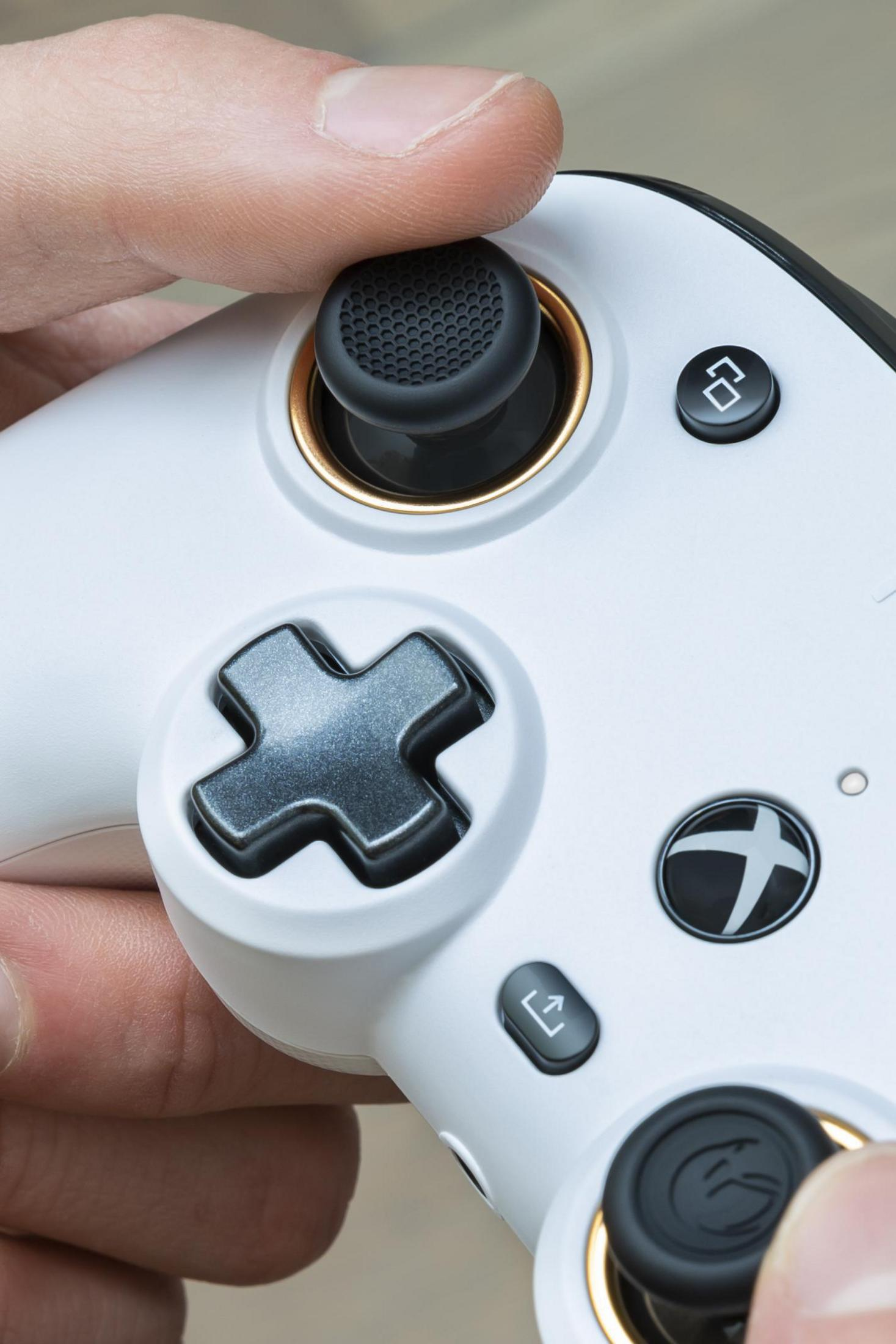 Zbliżenie białego kontrolera do gier. Widoczne są joystick, przyciski i krzyżak.