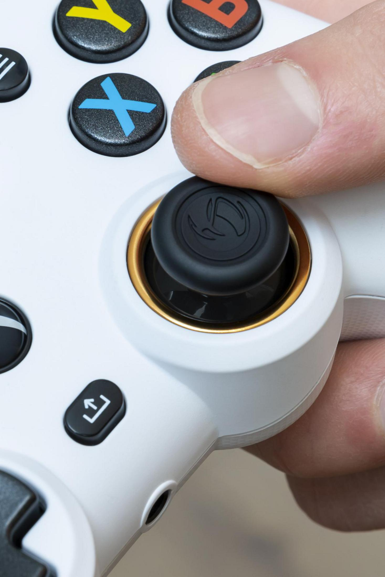 Dłoń naciskająca czarny joystick na białym kontrolerze do gier.