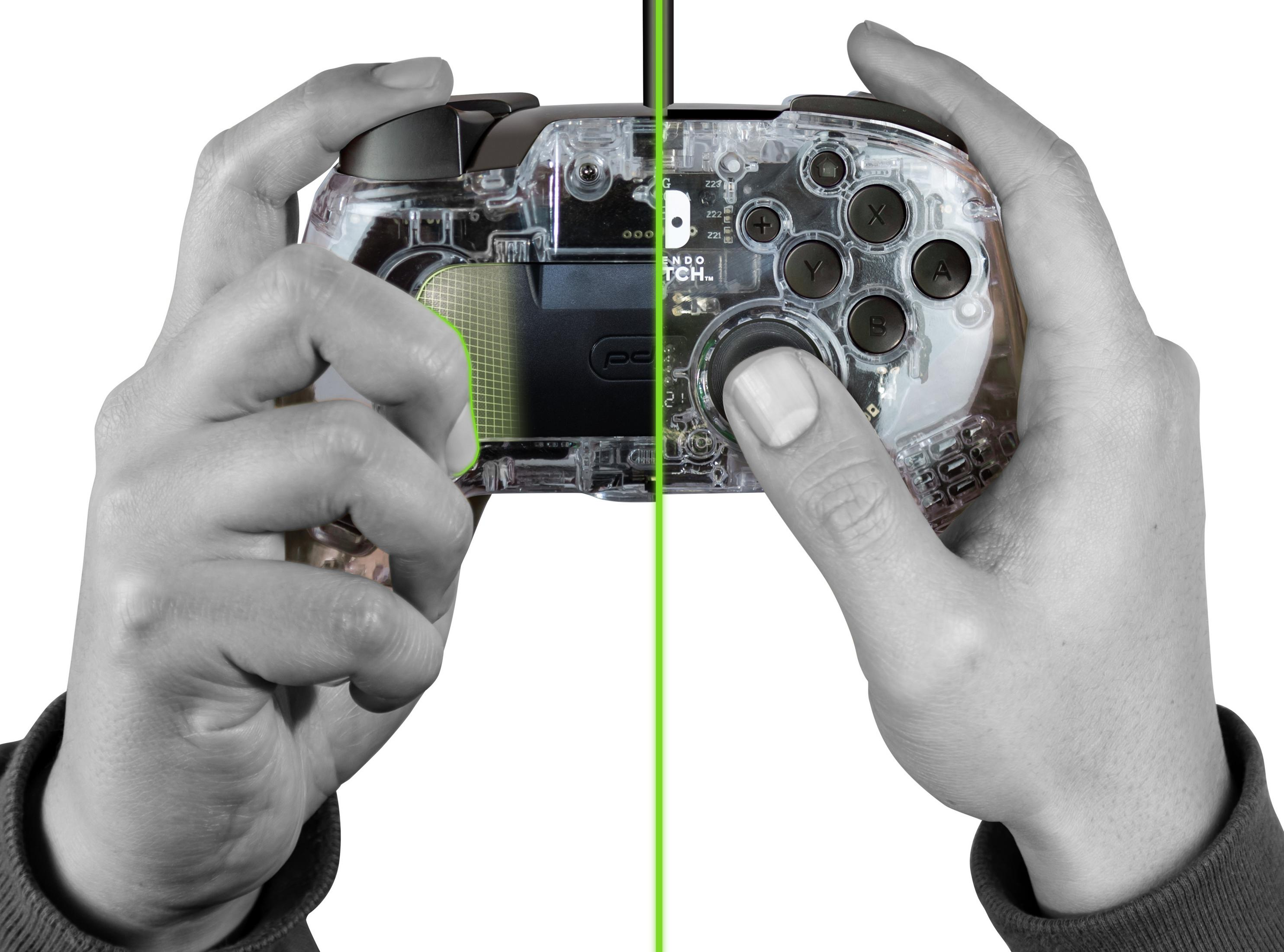 Dłonie trzymają przezroczysty kontroler do gier, podzielony zieloną linią. Białe tło.