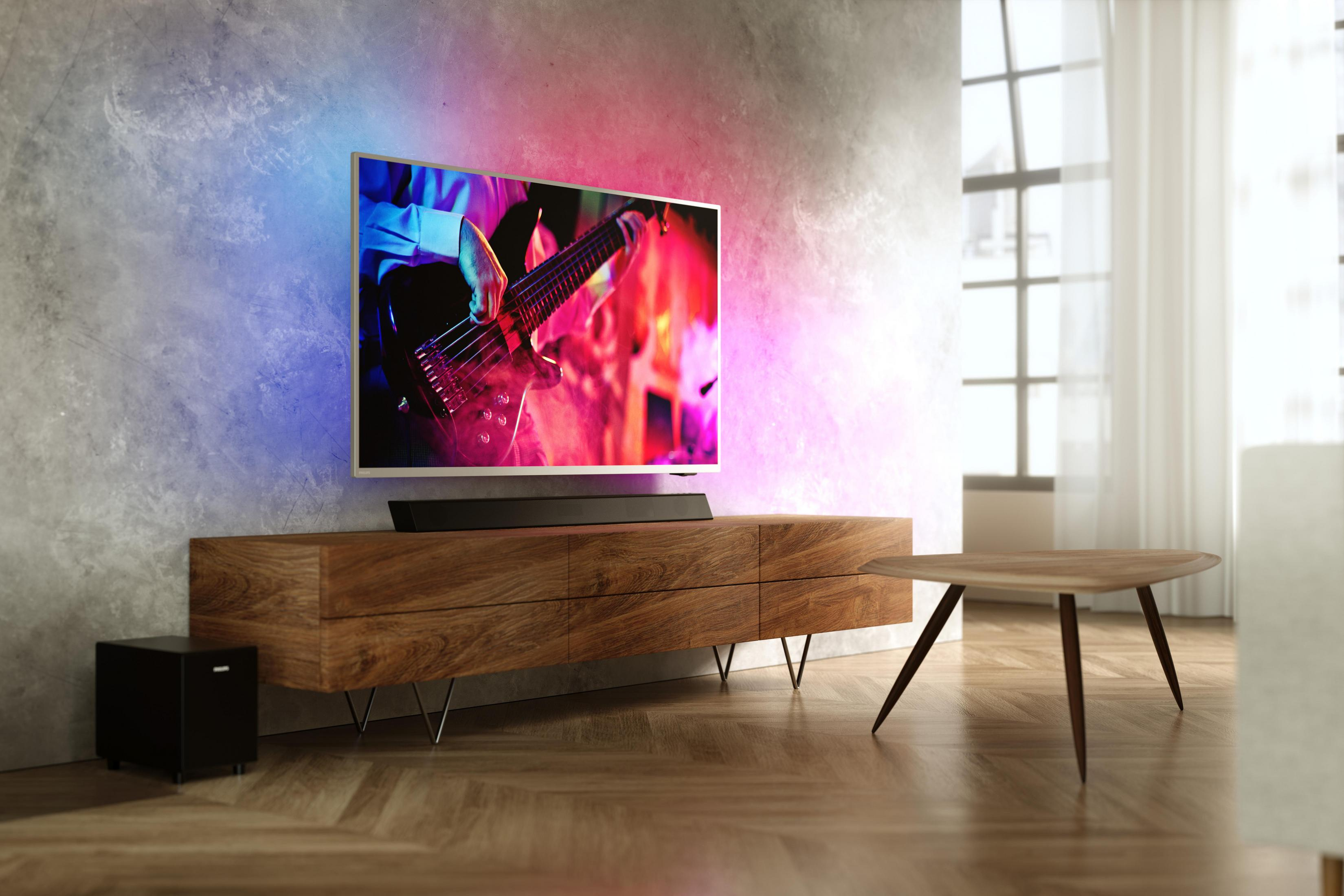 Una TV su un mobile in legno, con subwoofer. Un tavolo e una finestra nella stanza.
