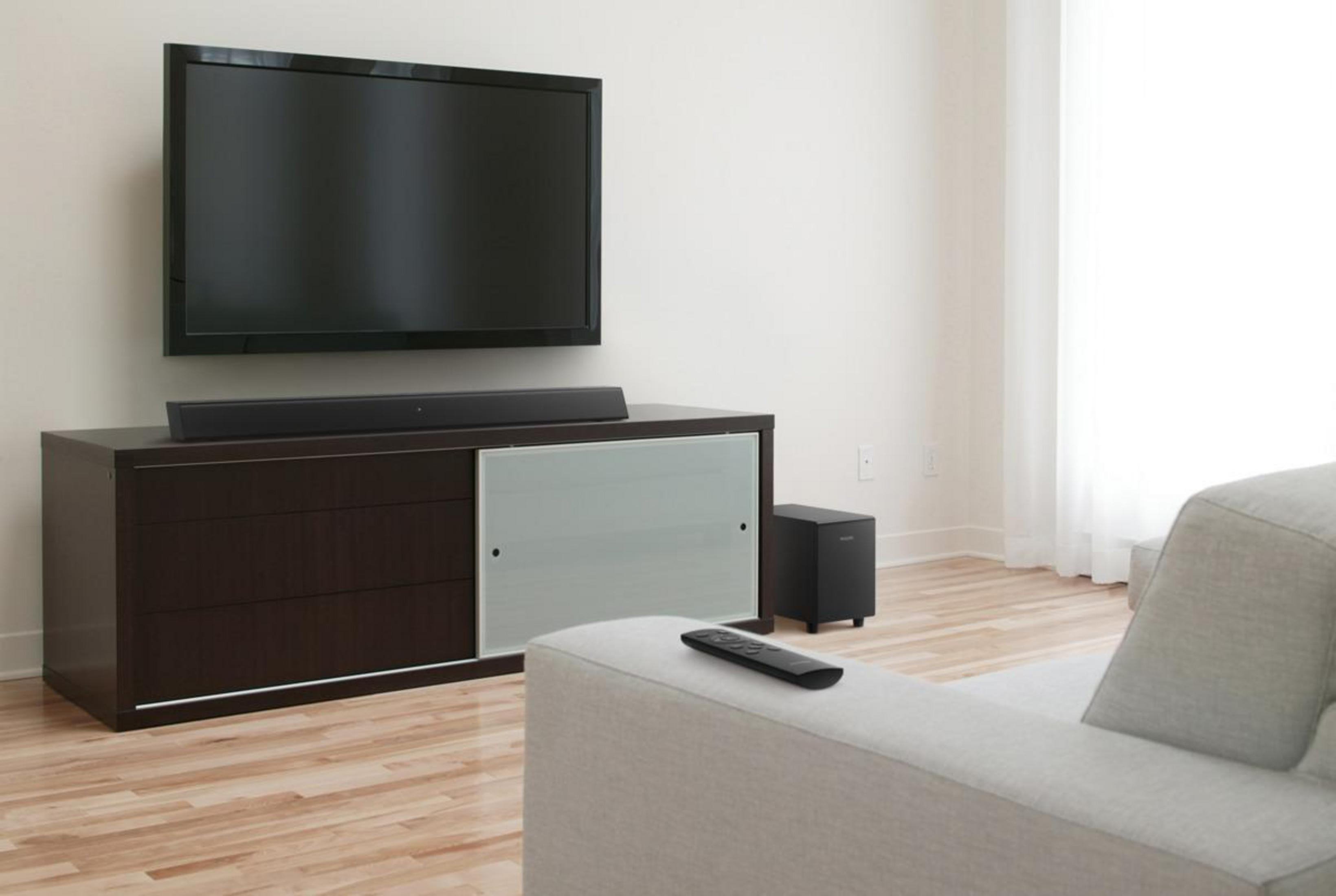 Configurazione soggiorno: TV su mobile scuro, soundbar, subwoofer e telecomando.