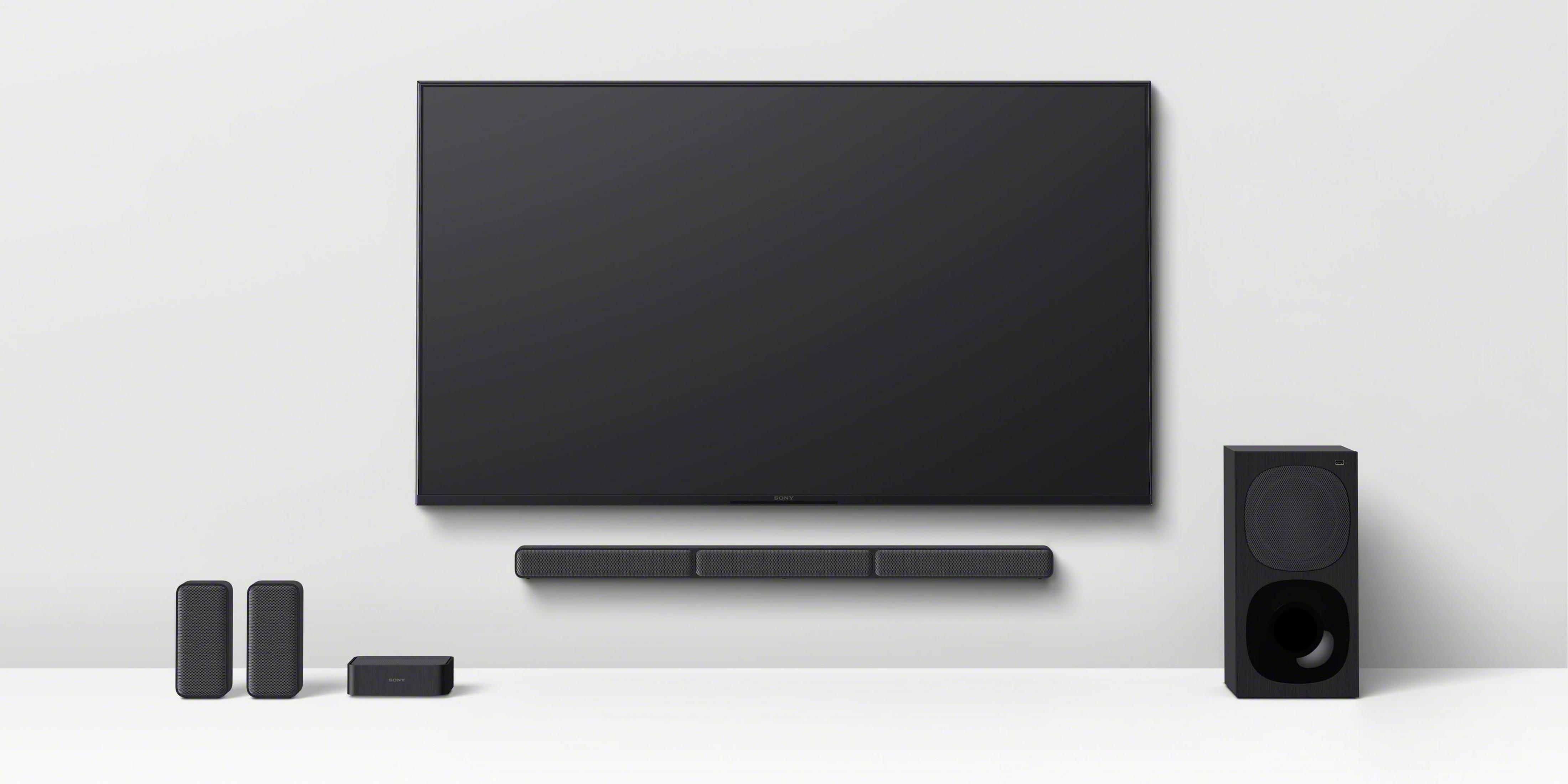 Ein Fernseher, eine Soundbar, ein Subwoofer und Lautsprecher auf weißem Untergrund.