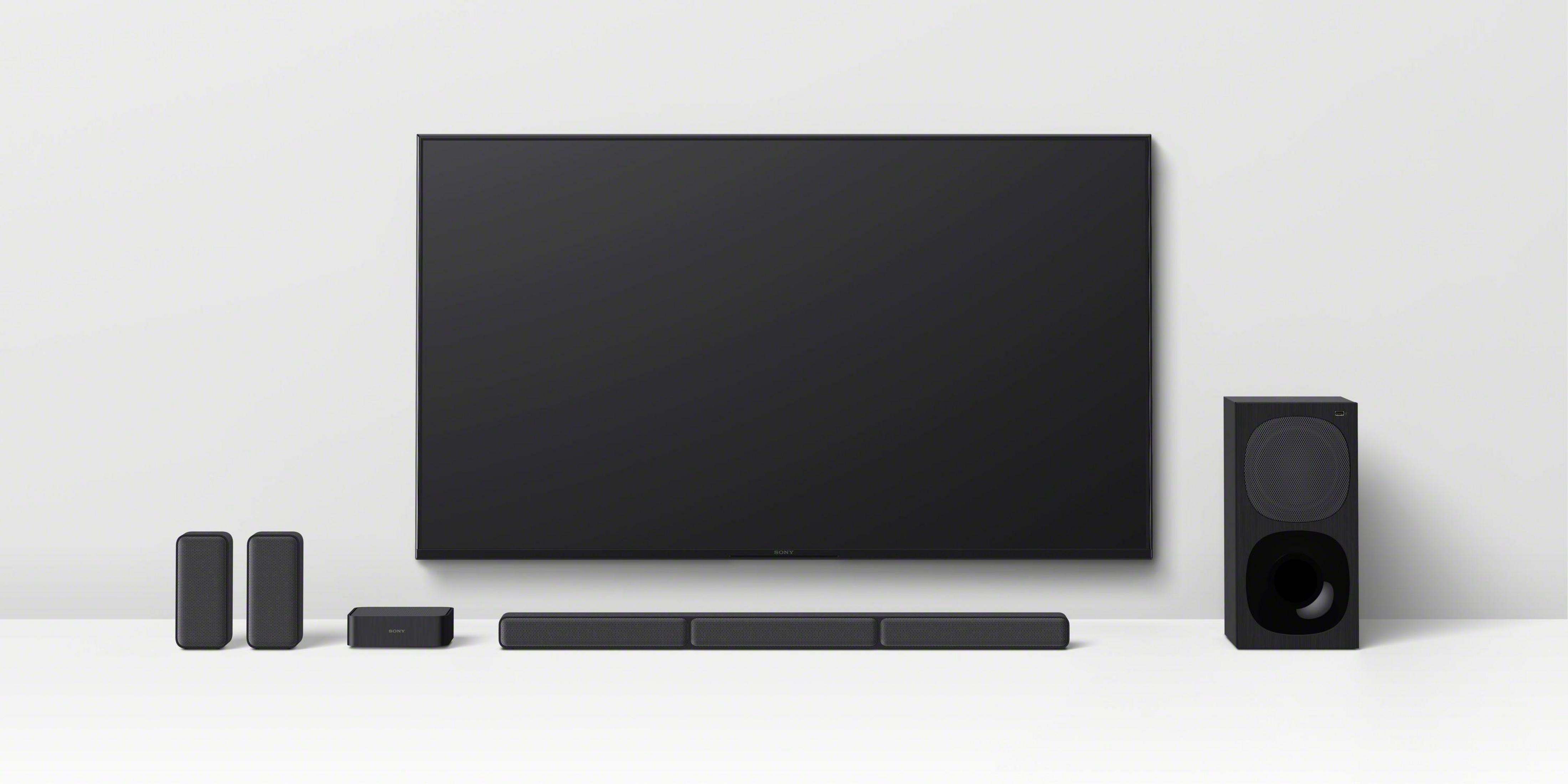 Ein Heimkino-Setup mit großem Fernseher, Soundbar und Lautsprechern.