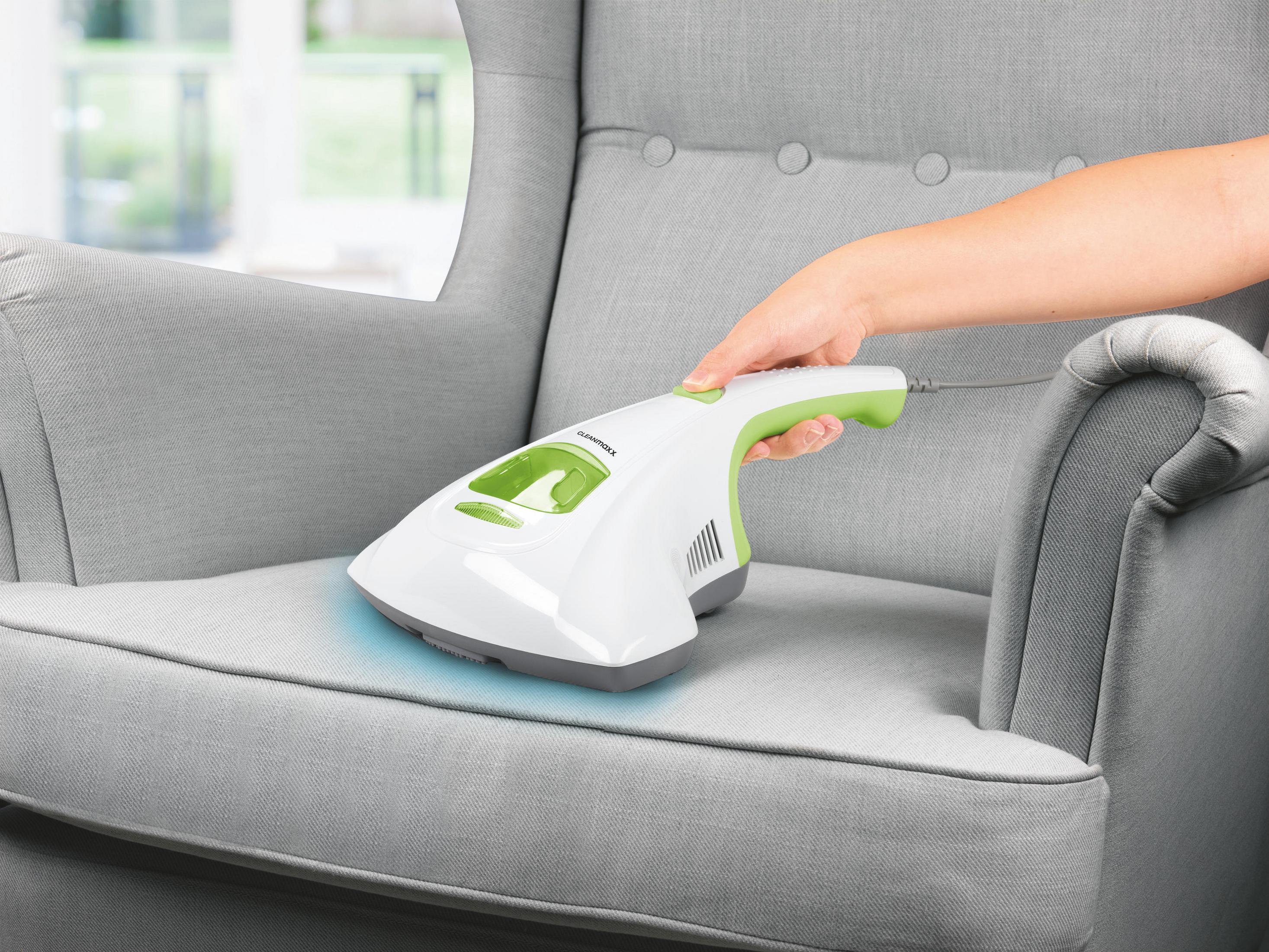Odkurzacz ręczny czyszczący szary fotel. Biały i zielony odkurzacz.