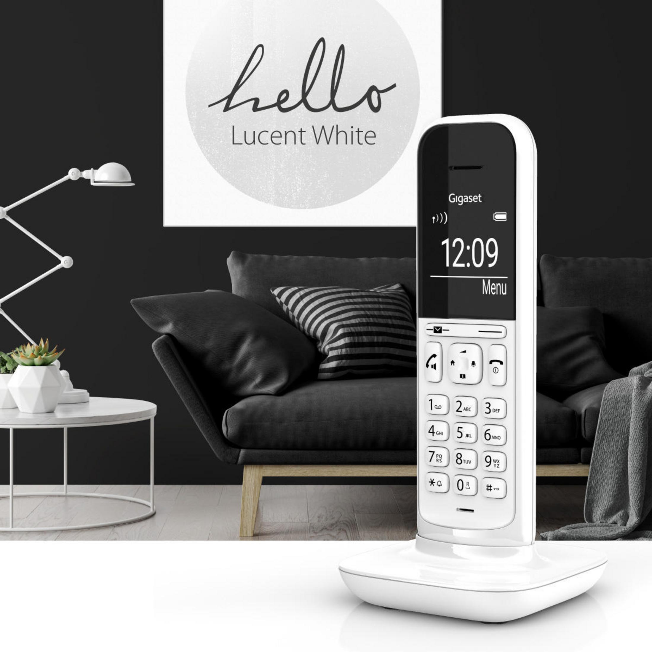 Un teléfono fijo blanco sobre una mesa, con una pintura en blanco y negro al fondo.
