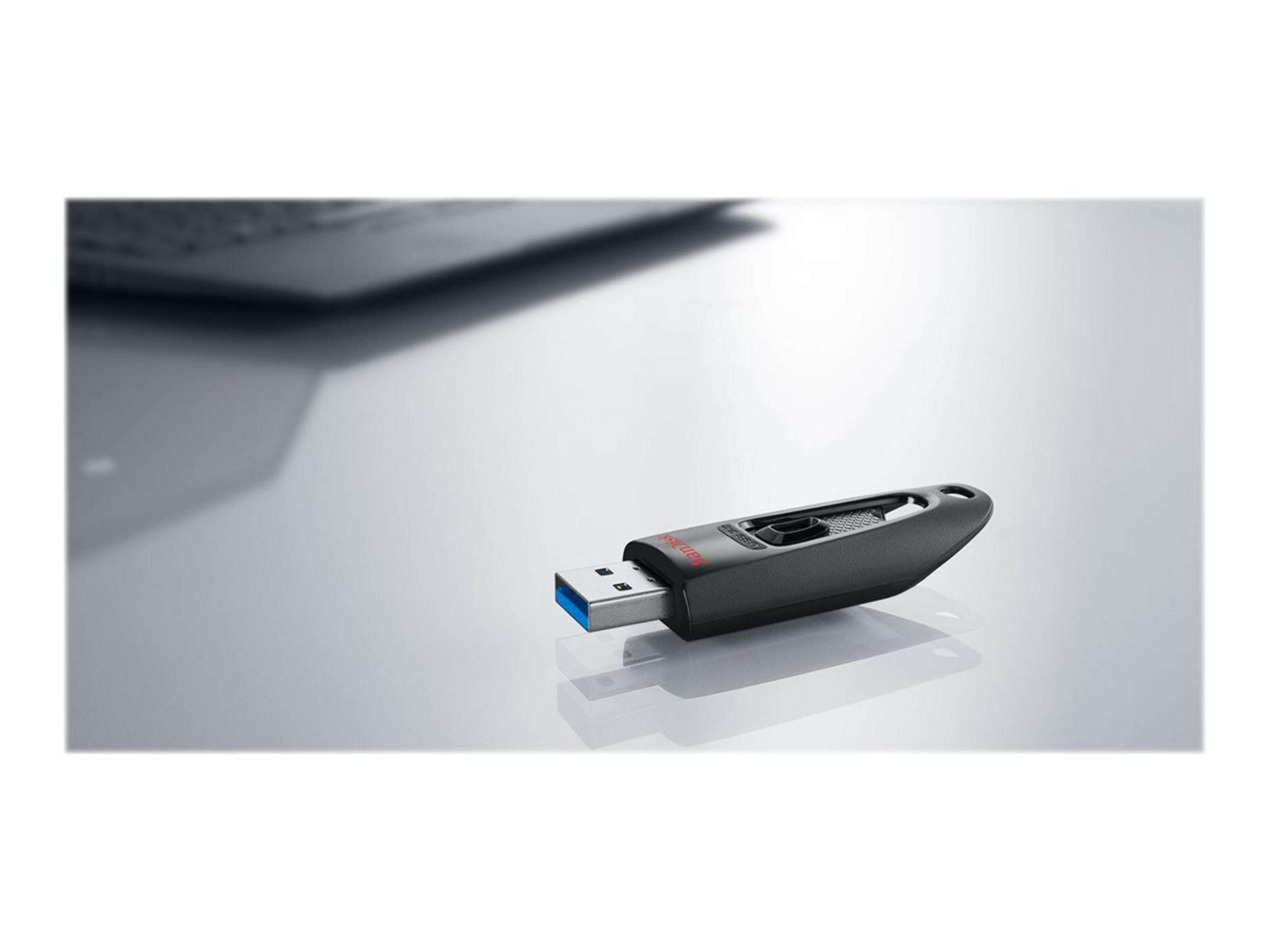 Una chiavetta USB nera con punta blu su superficie riflettente, un laptop sfocato.