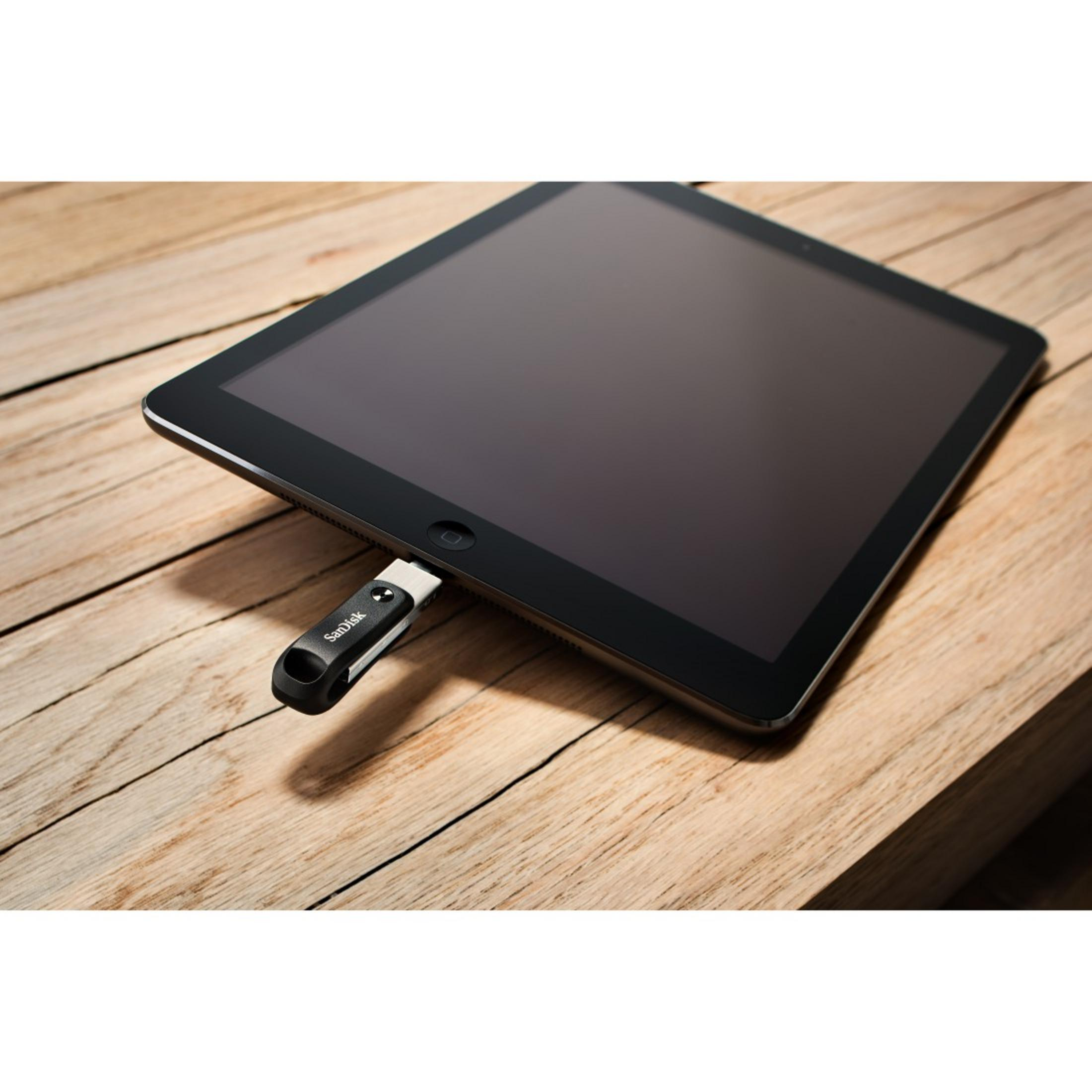 Tablet z włożonym dyskiem USB, leżący na drewnianej powierzchni.