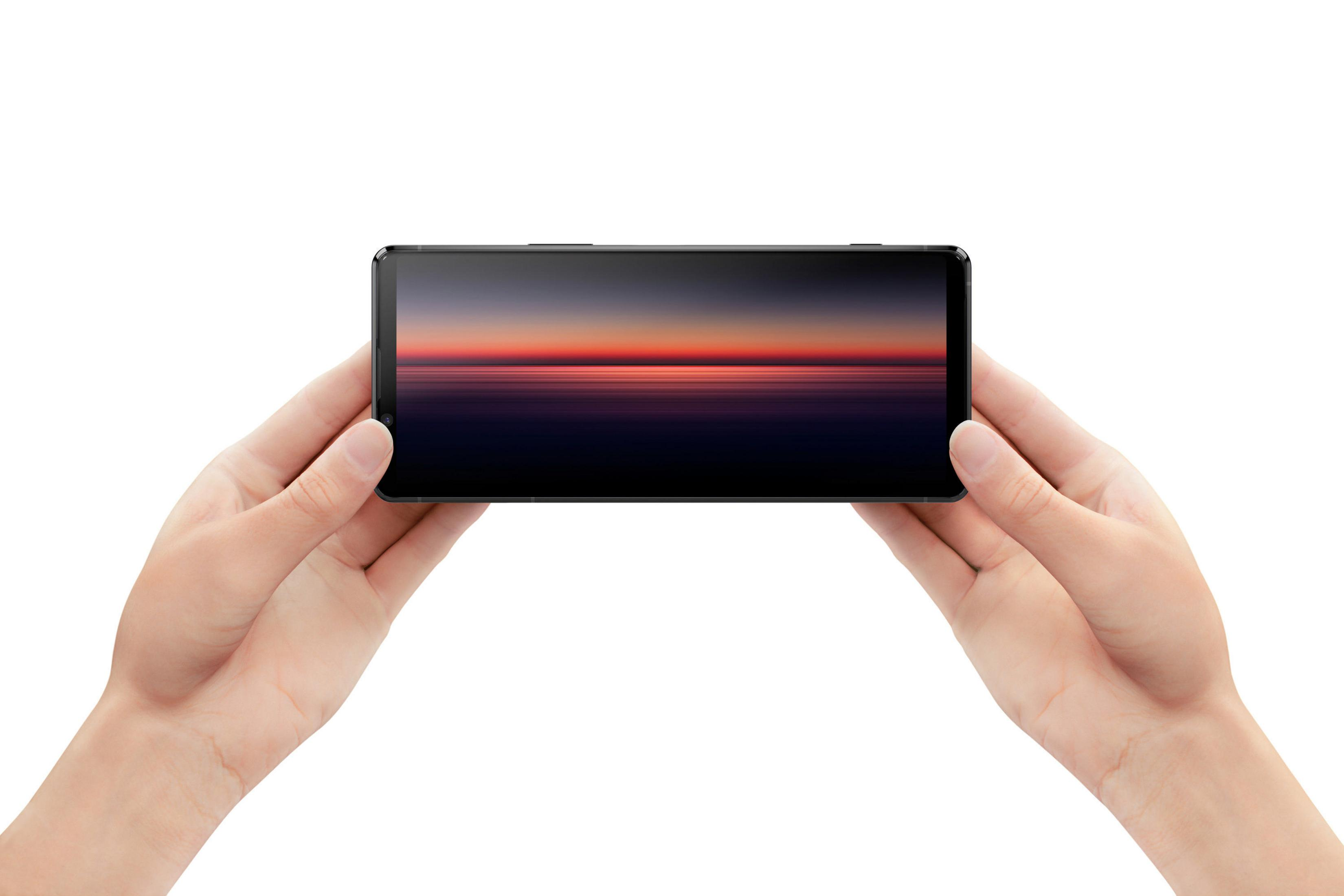 Hände halten ein Telefon horizontal, das ein Sonnenuntergangsbild anzeigt.