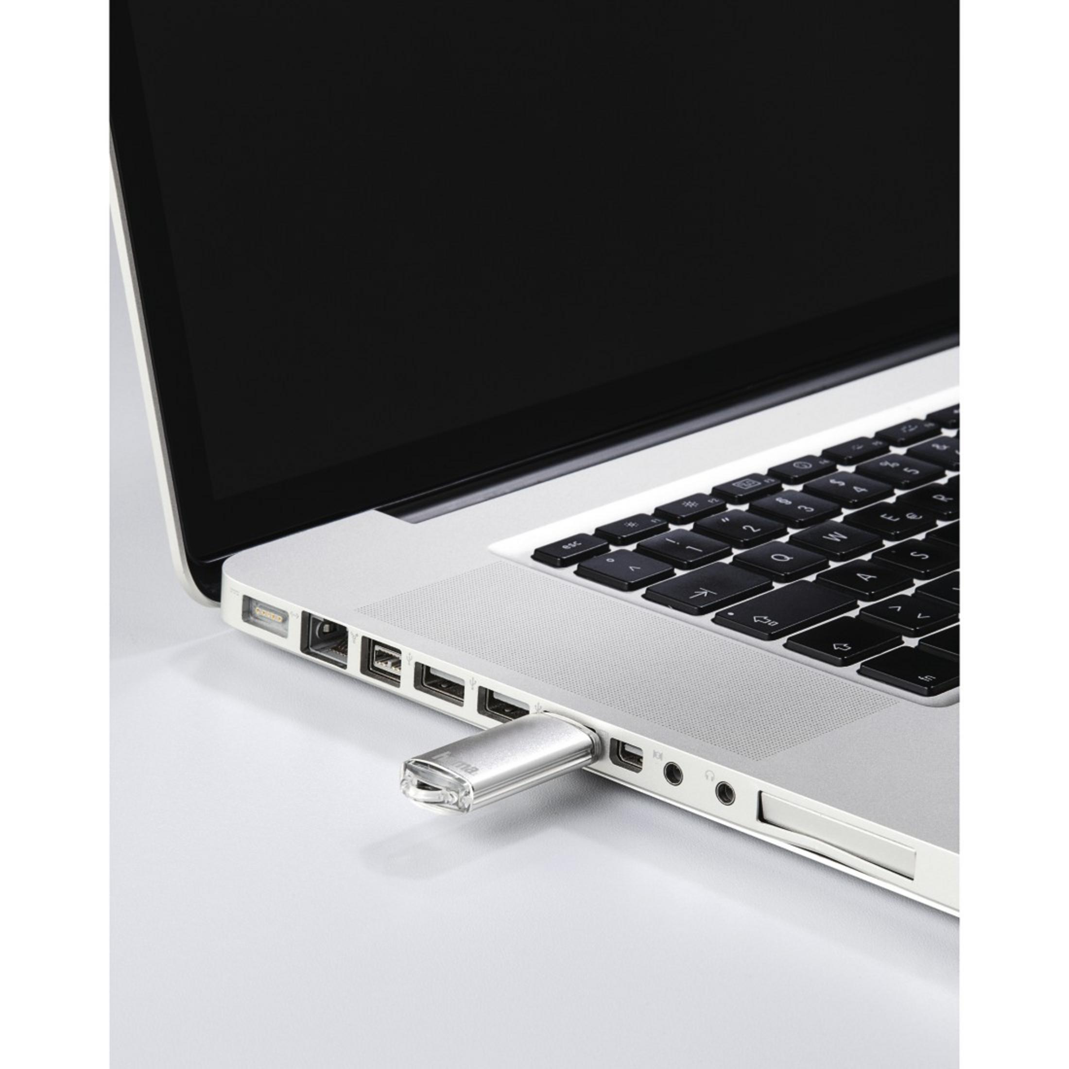 Srebrny pendrive włożony do laptopa. Laptop jest otwarty.