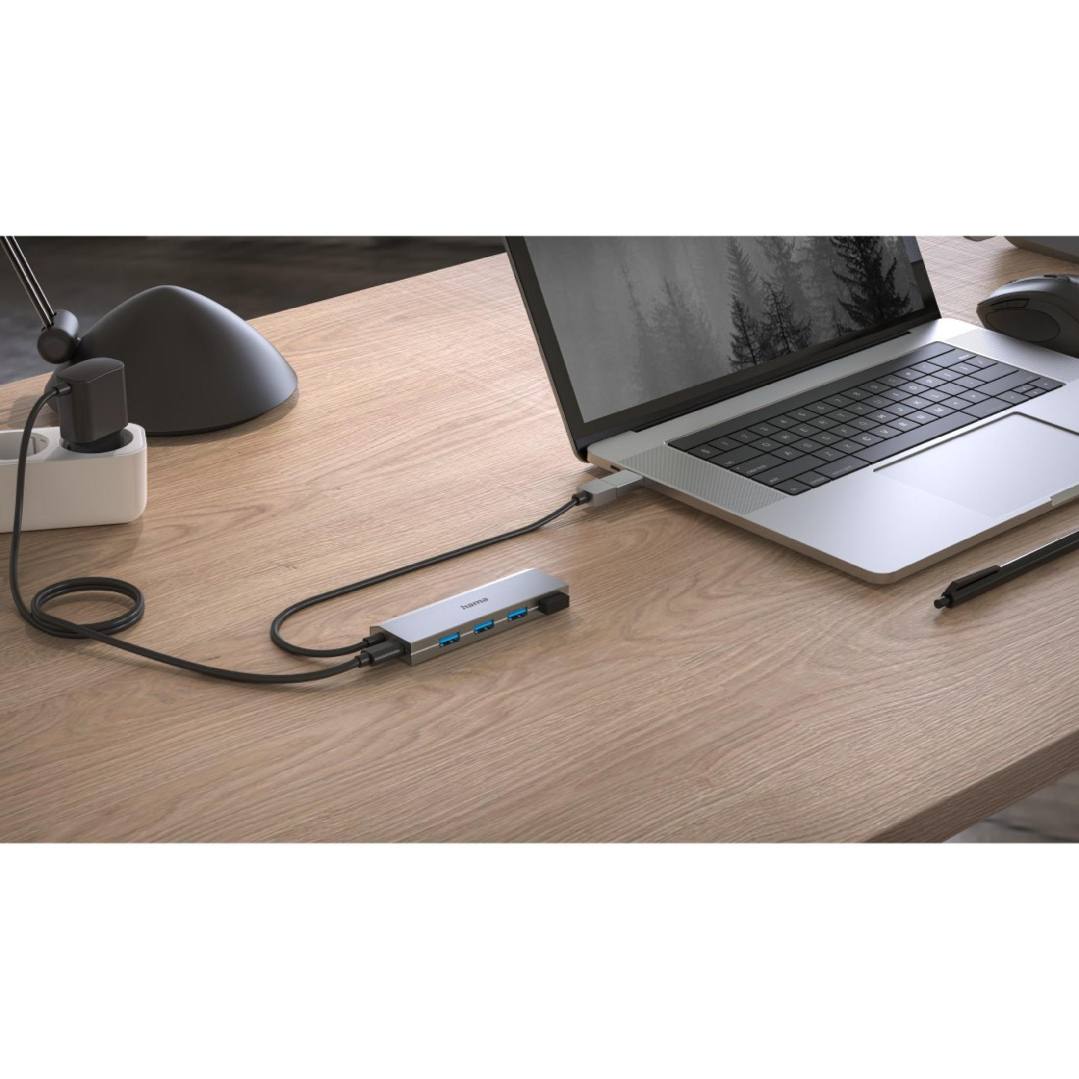 Un laptop collegato a un hub USB, mouse e adattatore di alimentazione, su una scrivania di legno.