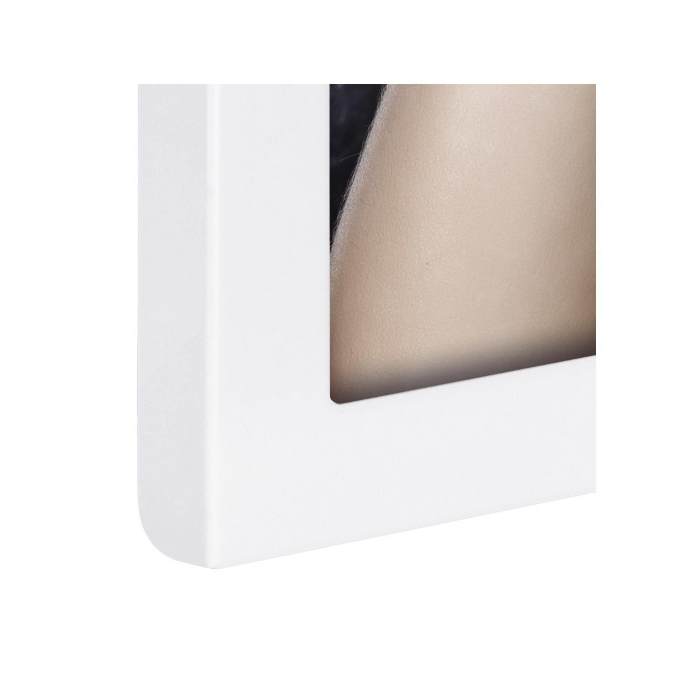 Nahaufnahme einer Ecke eines weißen Bilderrahmens, die Kante und eine beige Oberfläche zeigend.