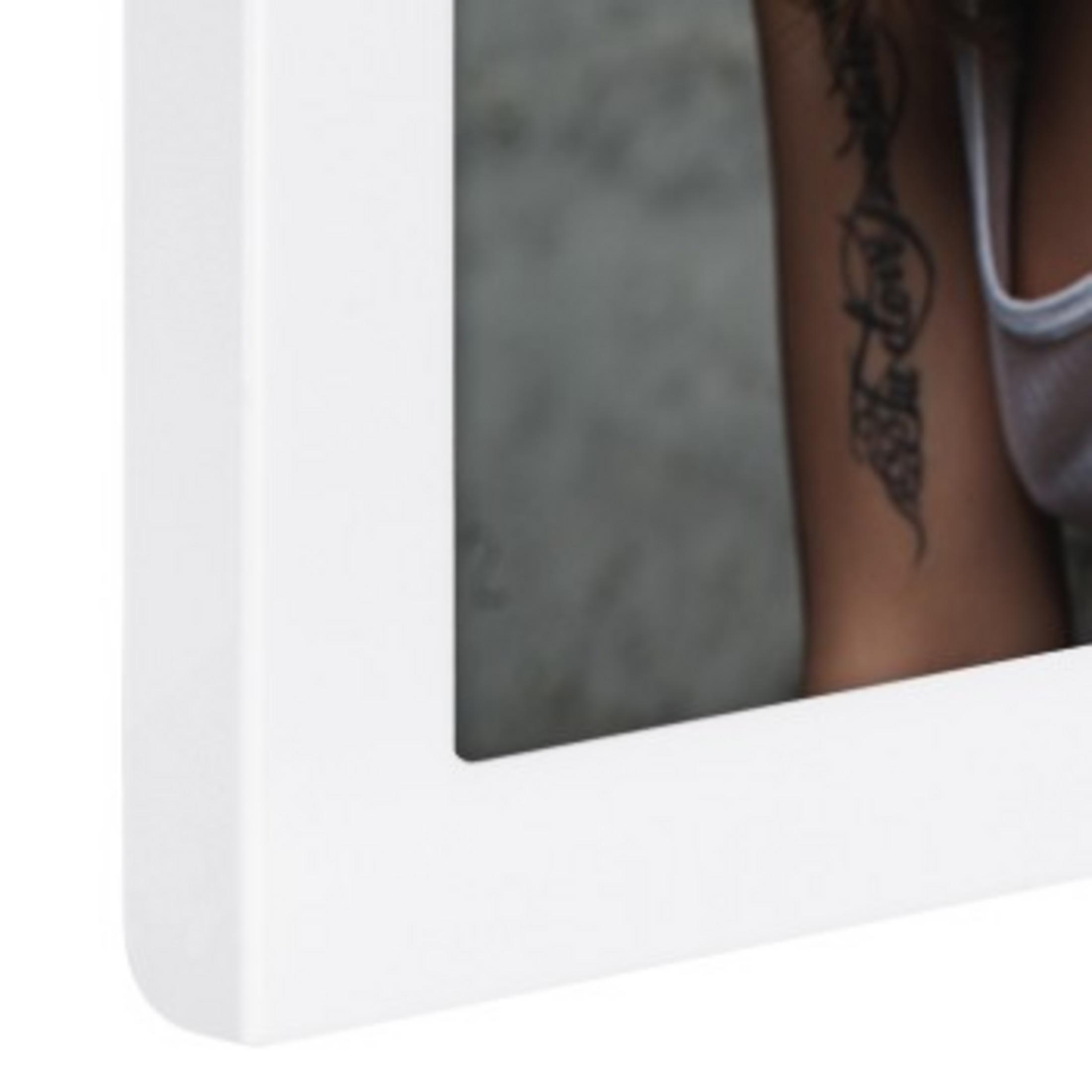 Nahaufnahme eines weißen Bilderrahmens, der den Arm einer Frau mit Tattoo zeigt.