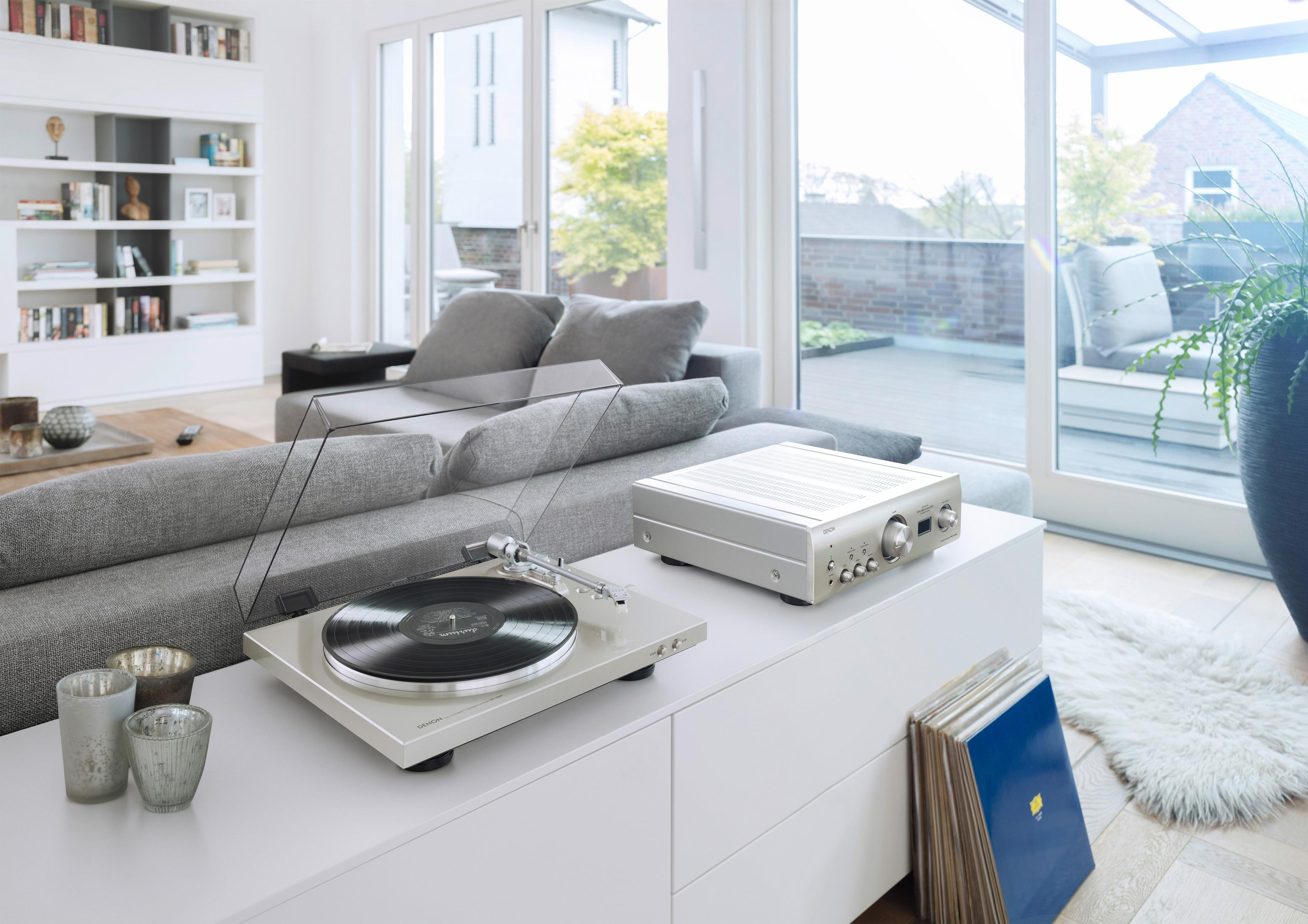 Gramofon, wzmacniacz i płyty na białej szafce w salonie.