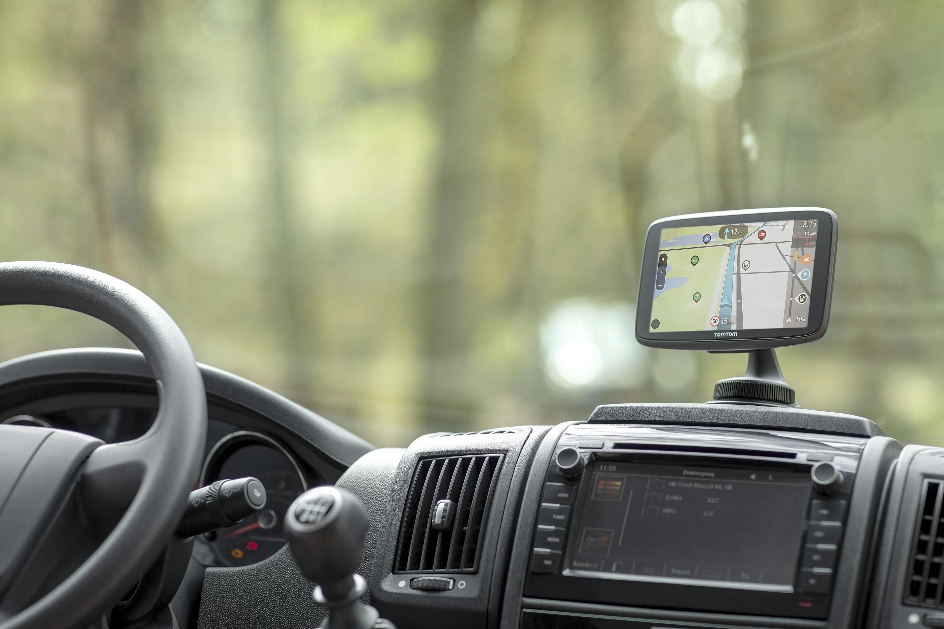 System nawigacji GPS zamontowany na desce rozdzielczej samochodu. Tło: rozmyty las.