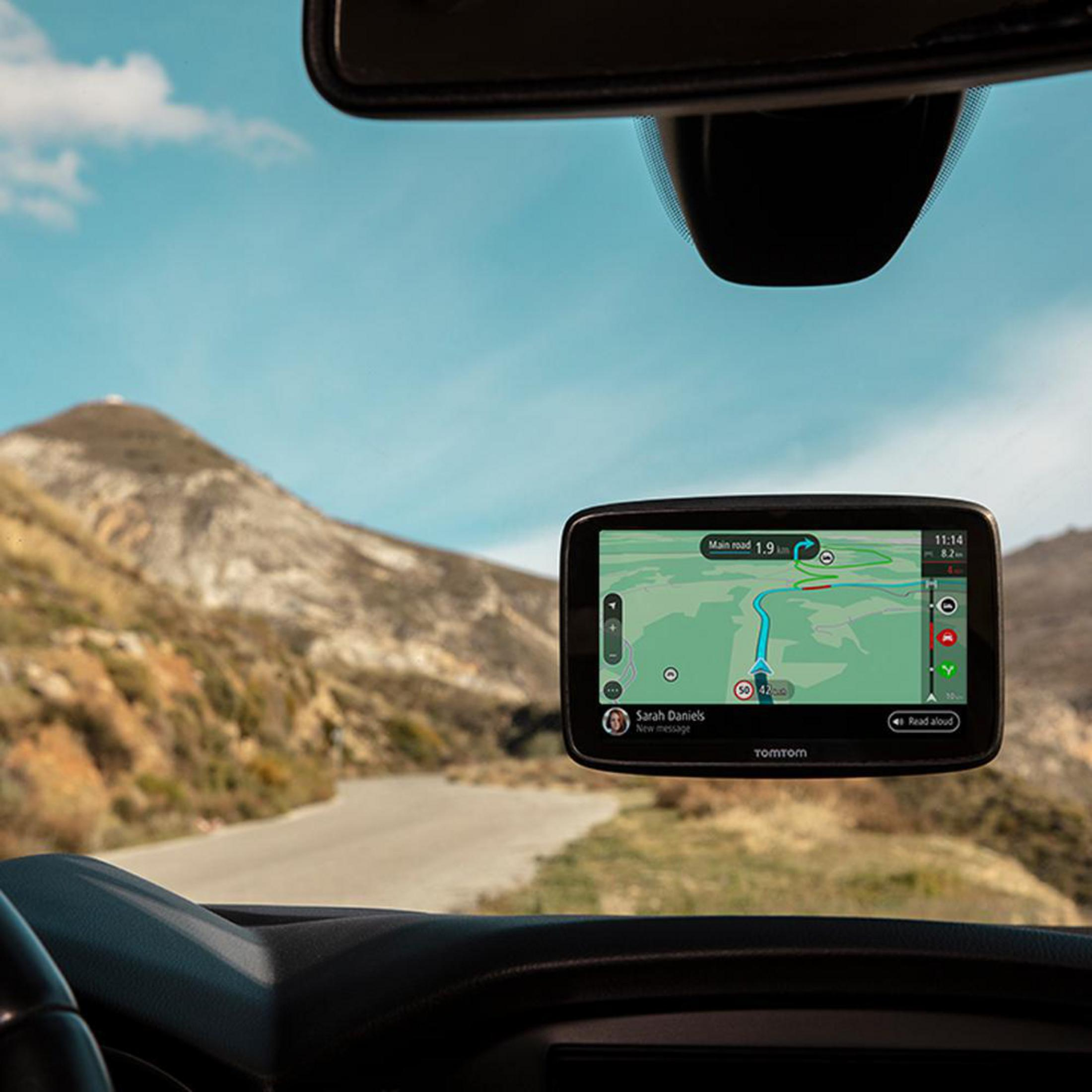 GPS-Navigationsgerät in einem Auto. Der Bildschirm zeigt eine Karte. Blauer Himmel und Berg im Hintergrund.
