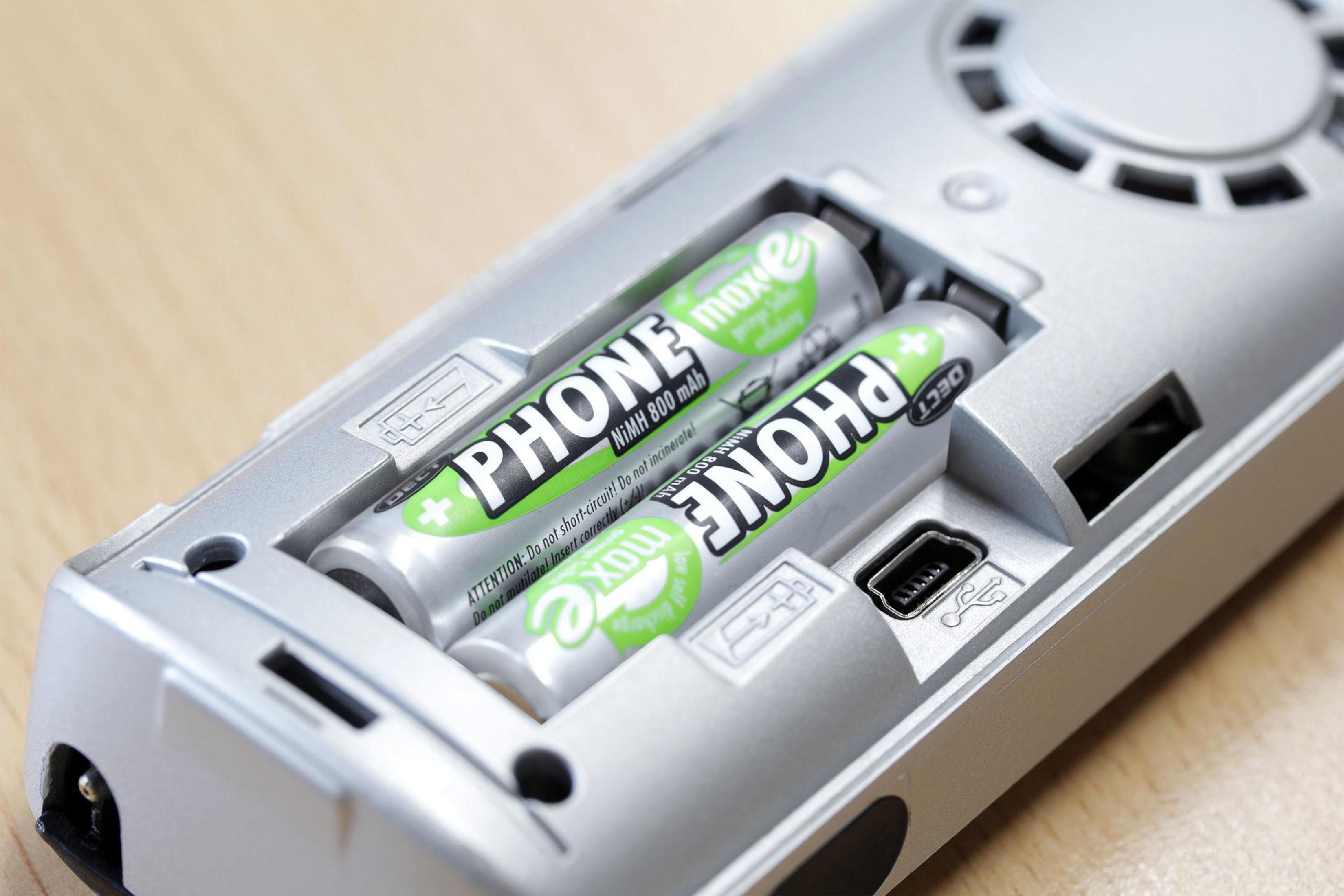 Due batterie verdi e grigie sono all'interno di uno scomparto batterie argentato aperto.