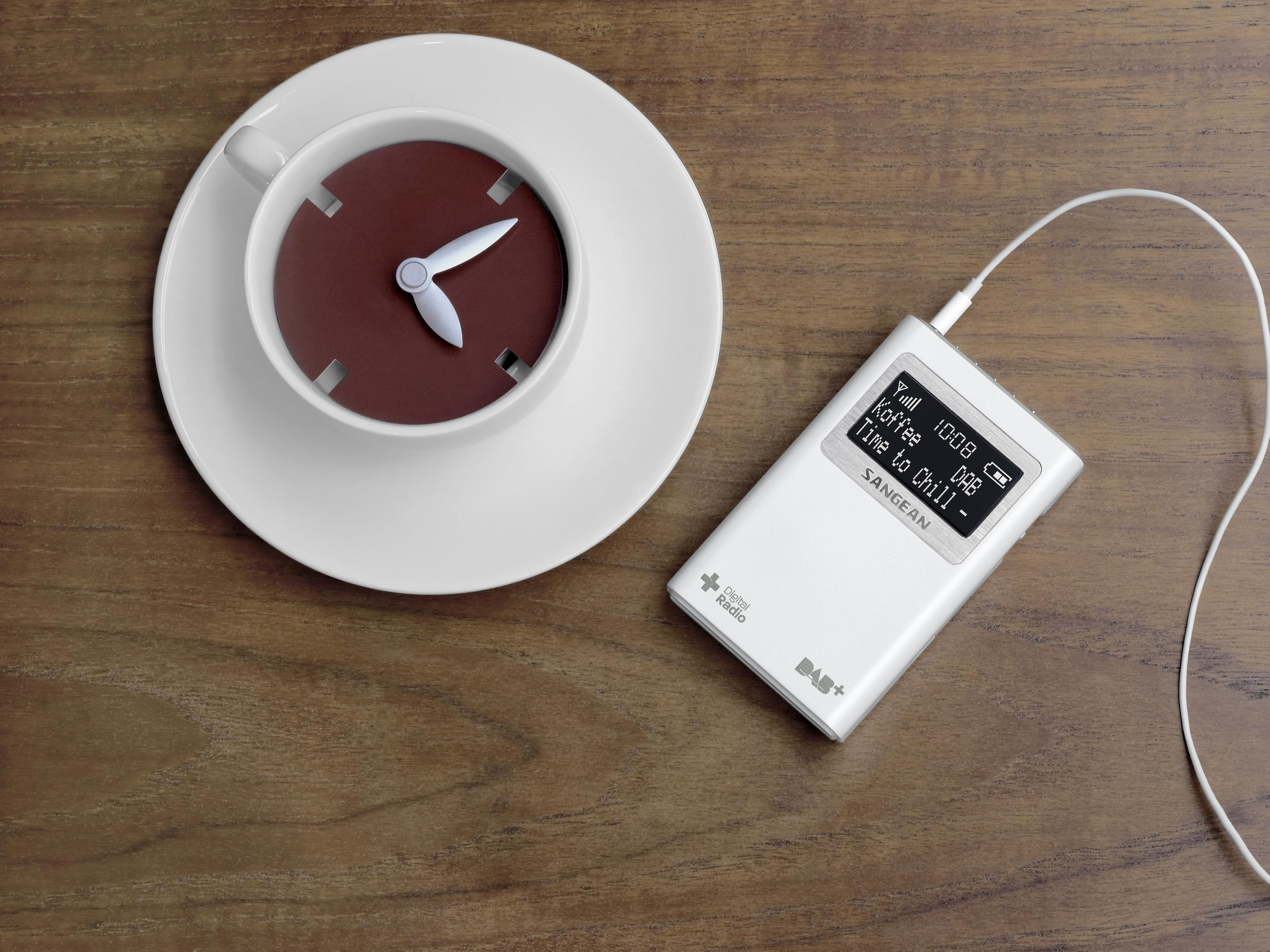 Zegar z filiżanki kawy, radio cyfrowe, drewniana powierzchnia.