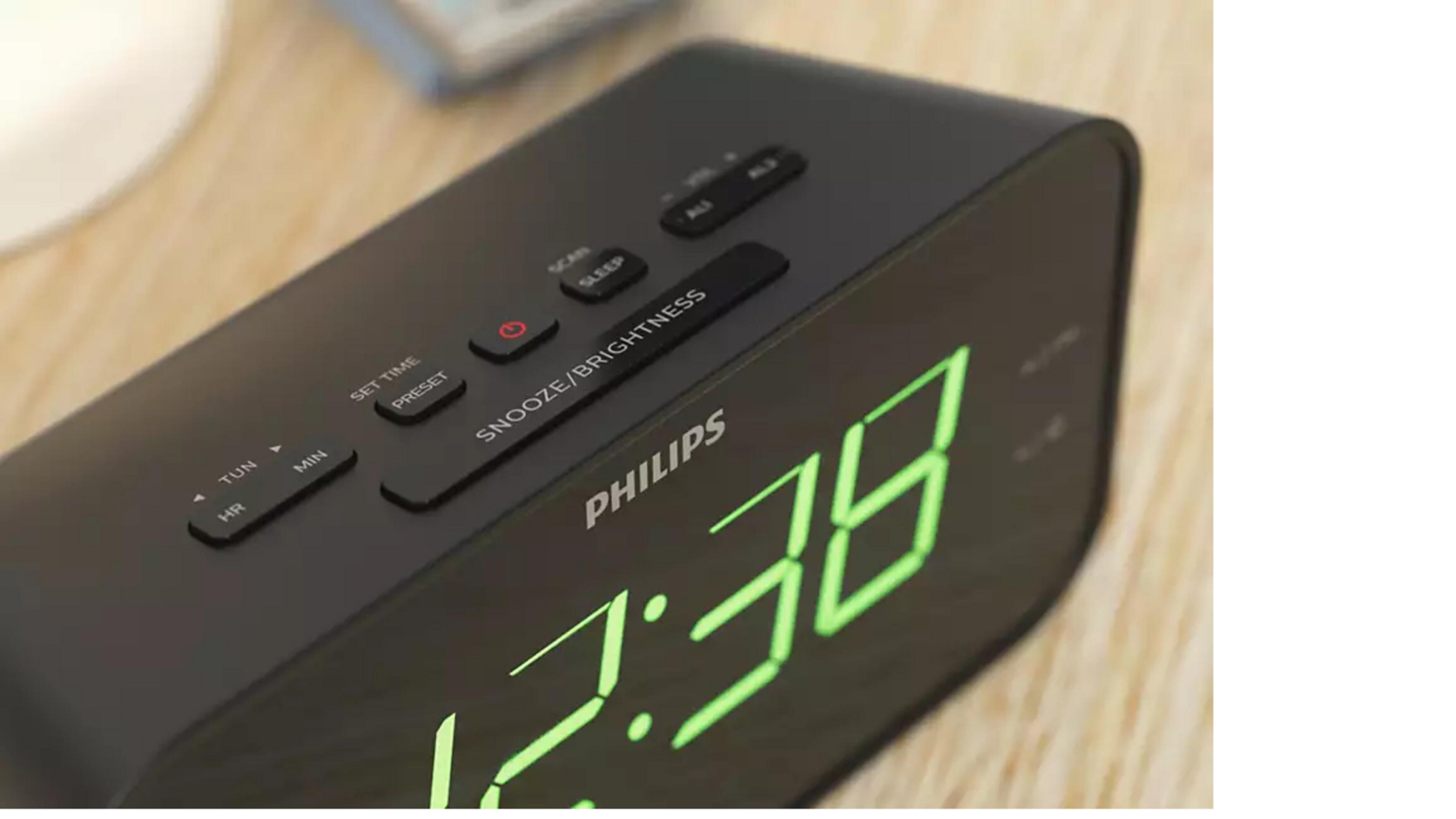 Réveil Philips noir avec chiffres verts numériques et plusieurs boutons dessus.