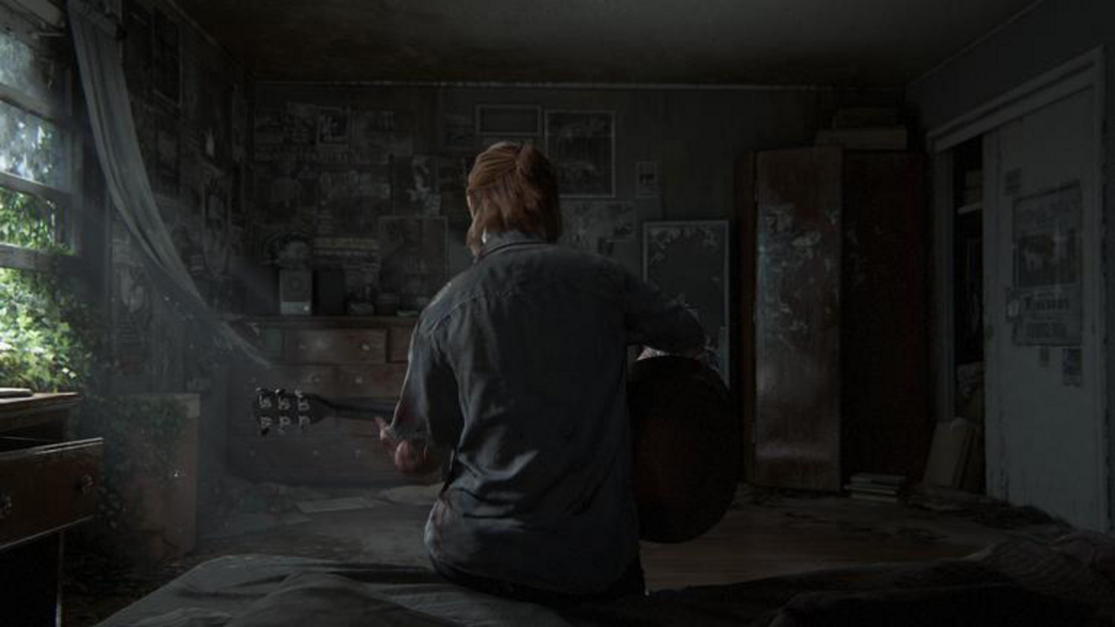 Una persona seduta sul letto suona la chitarra in una stanza scarsamente illuminata.