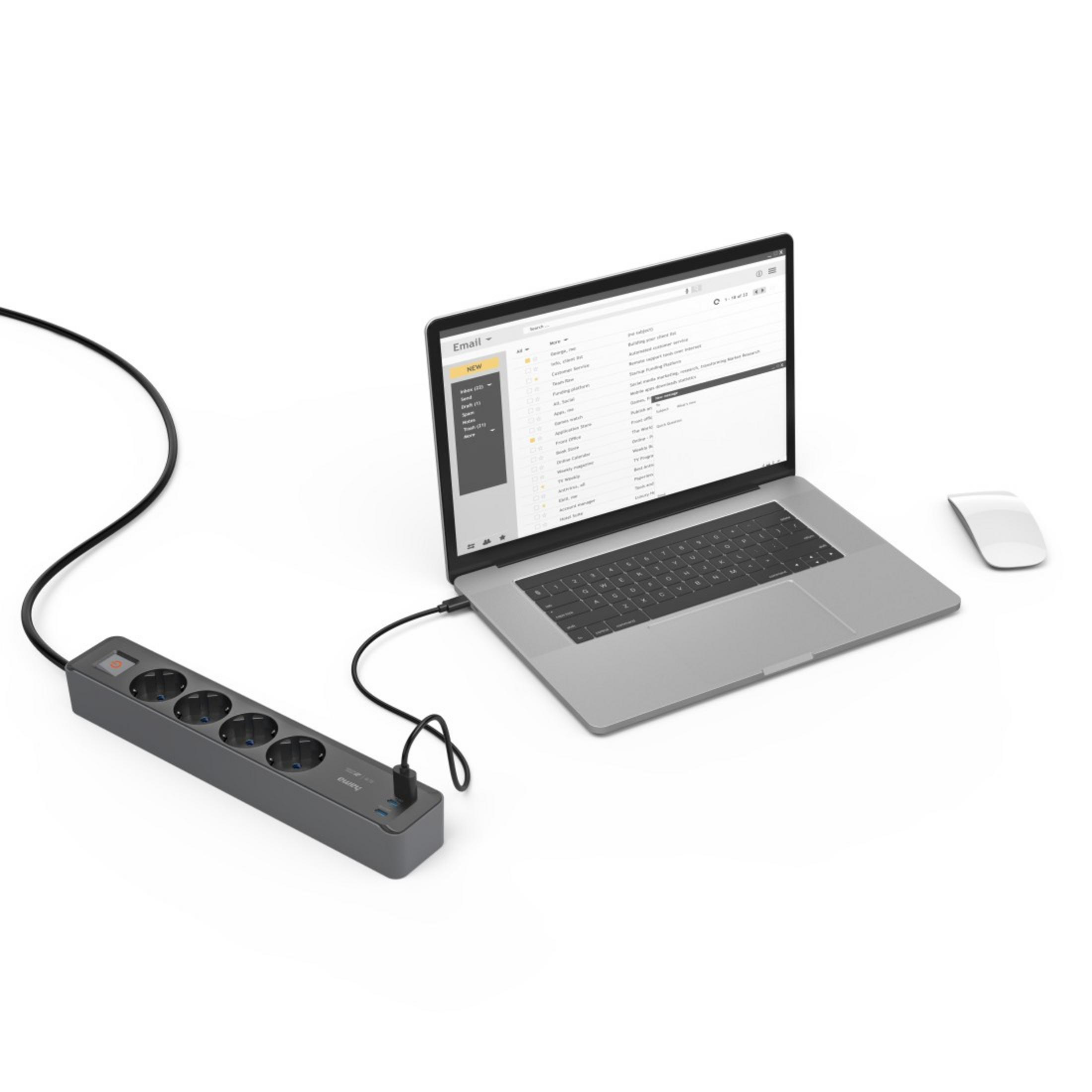 Laptop podłączony do listwy zasilającej i mysz na białej powierzchni.
