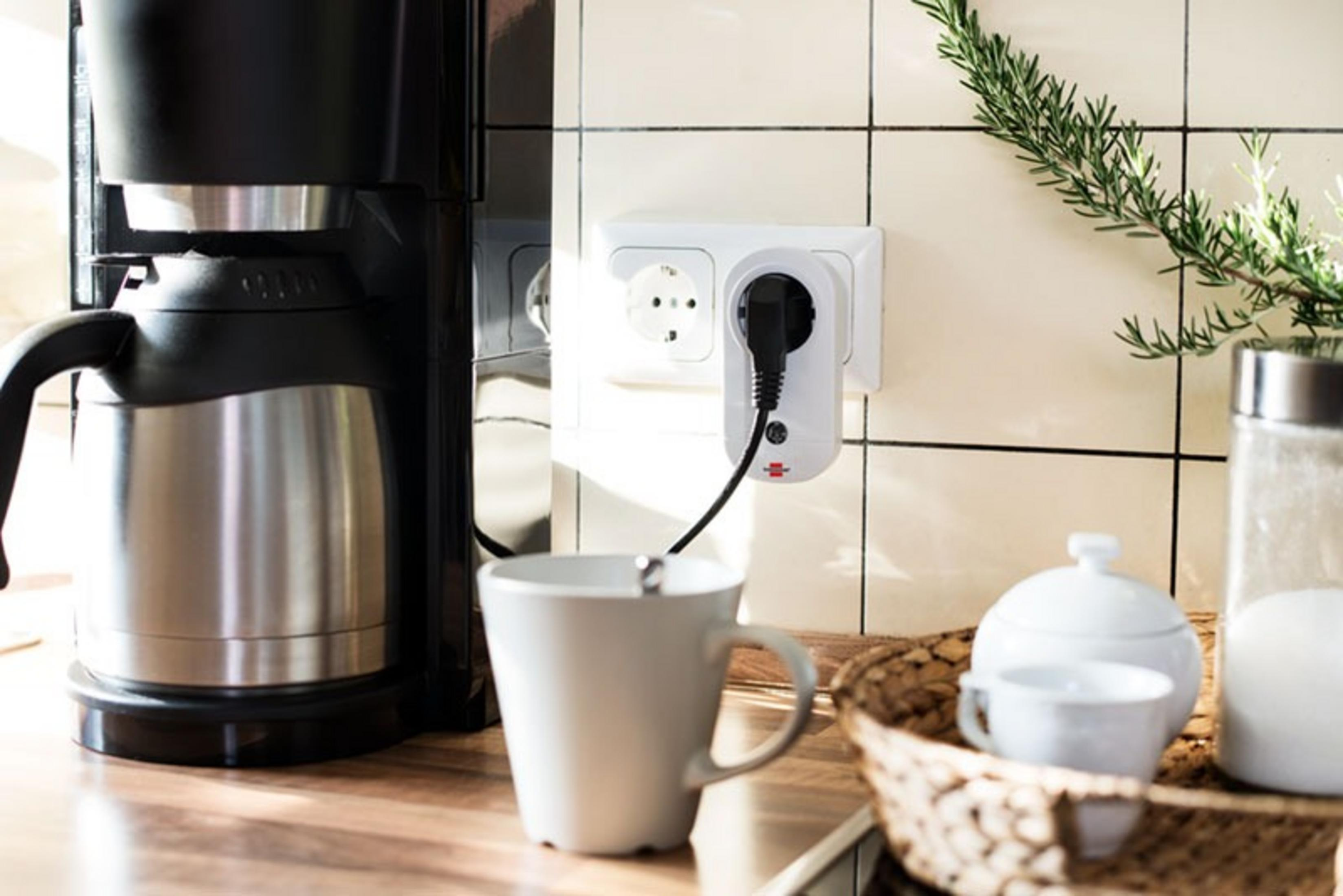 Eine Küchenszene mit Kaffeemaschine, Tasse und Smart Plug. Ein Korb und eine Zuckerdose sind ebenfalls vorhanden.