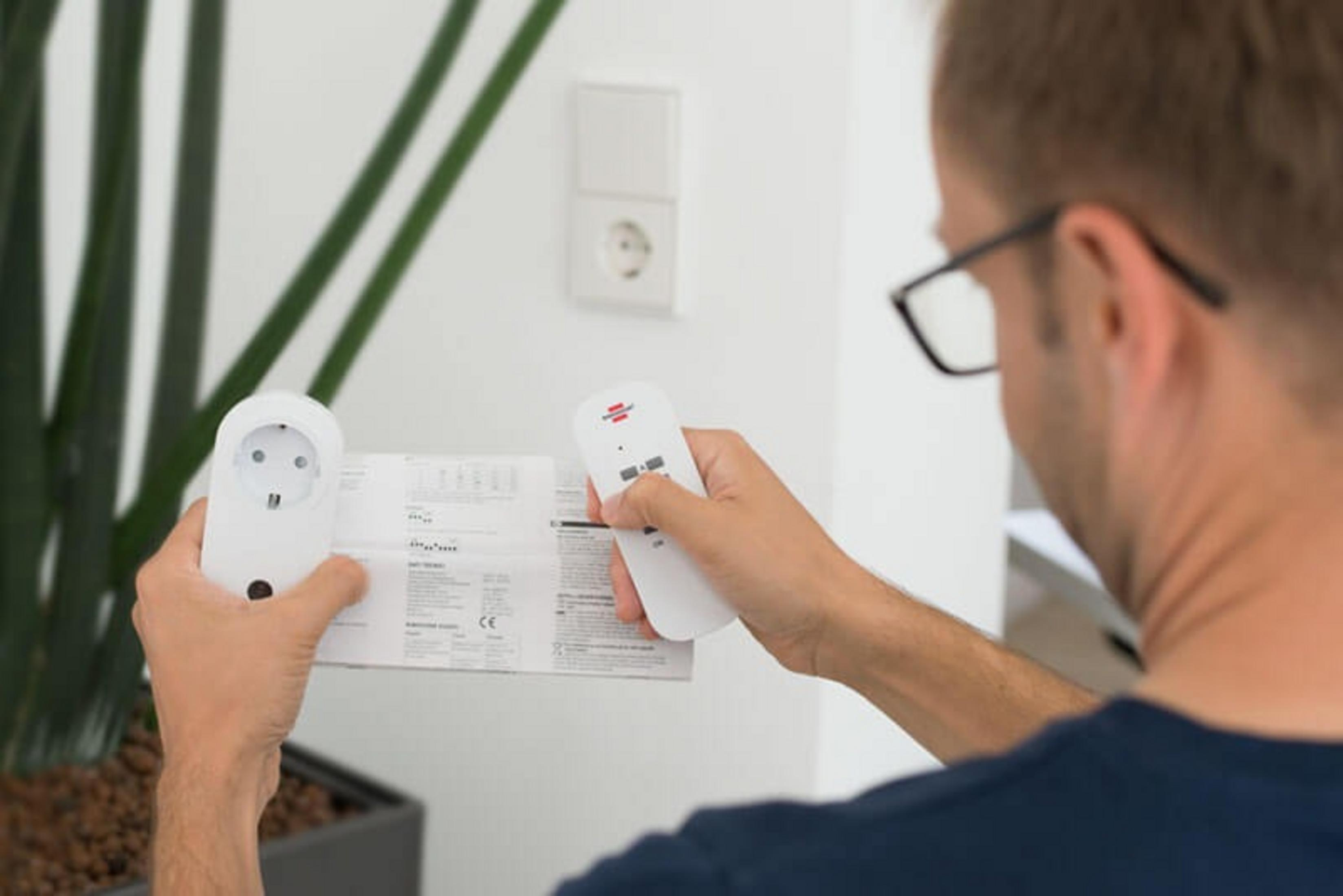Ein Mann liest Anweisungen, hält eine Fernbedienung und einen Smart-Stecker.