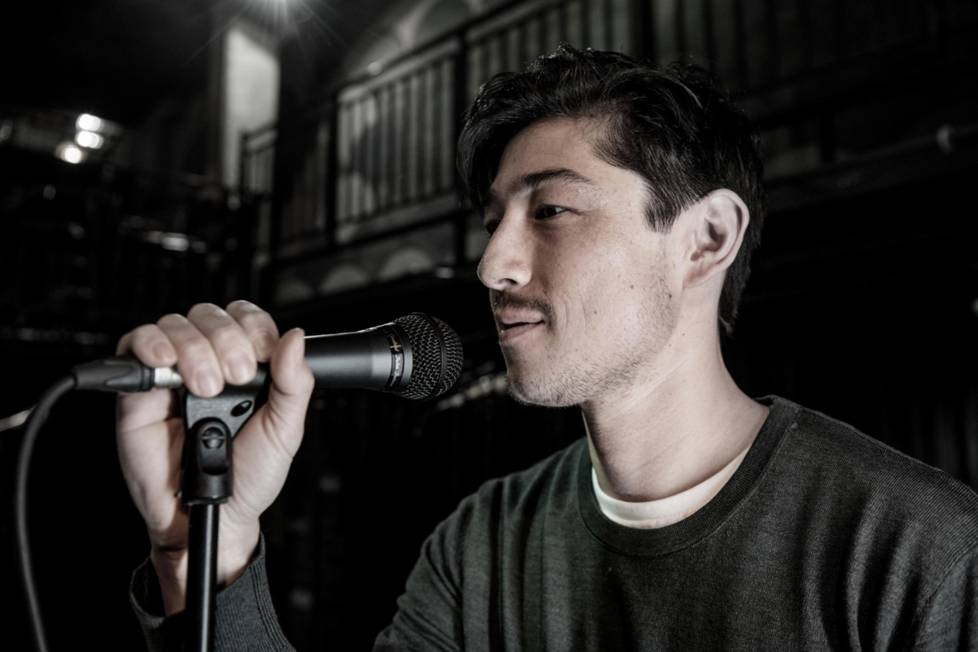 Mężczyzna z mikrofonem, w ciemnym otoczeniu.