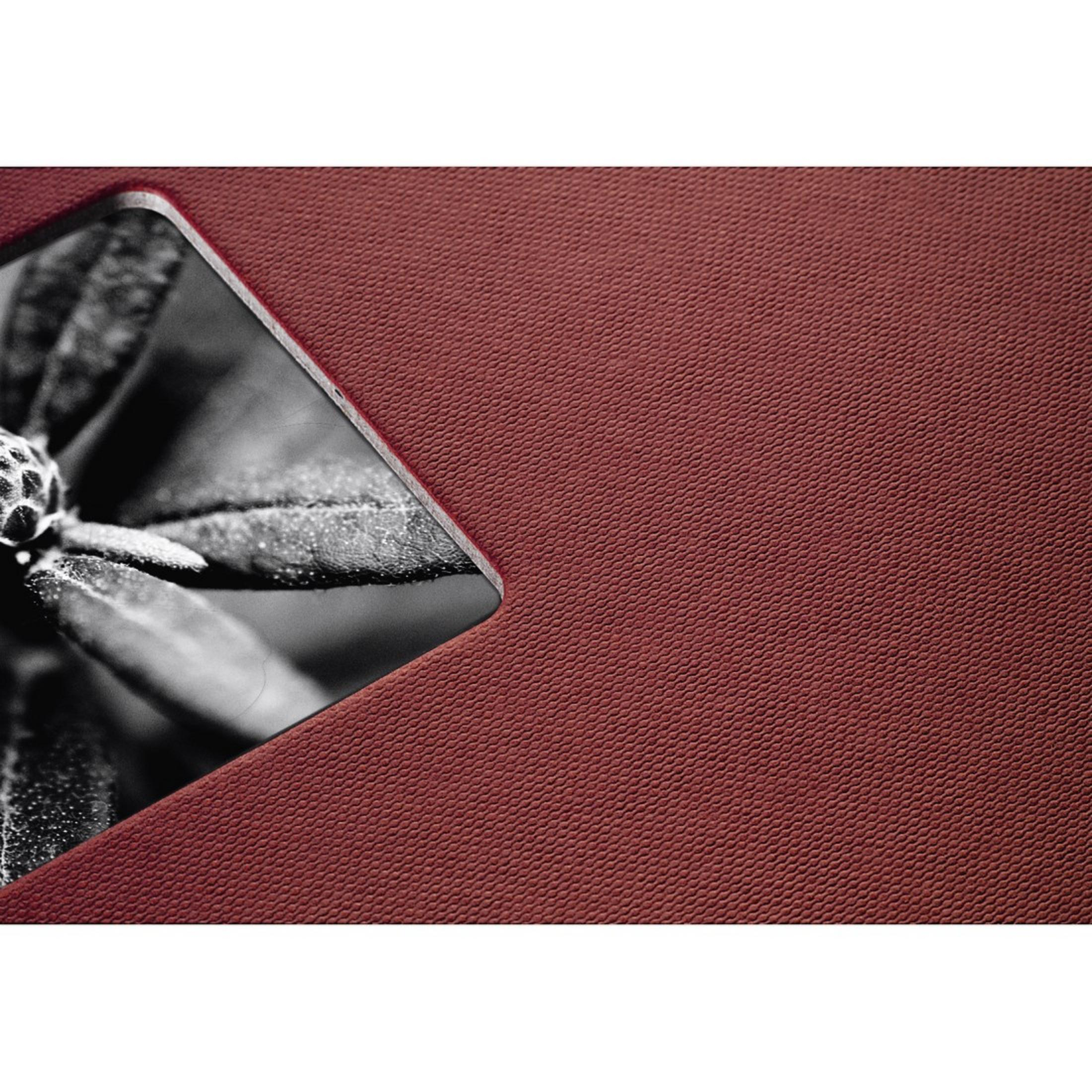 Zbliżenie teksturowanej, ciemnoczerwonej powierzchni z czarno-białym obrazem.