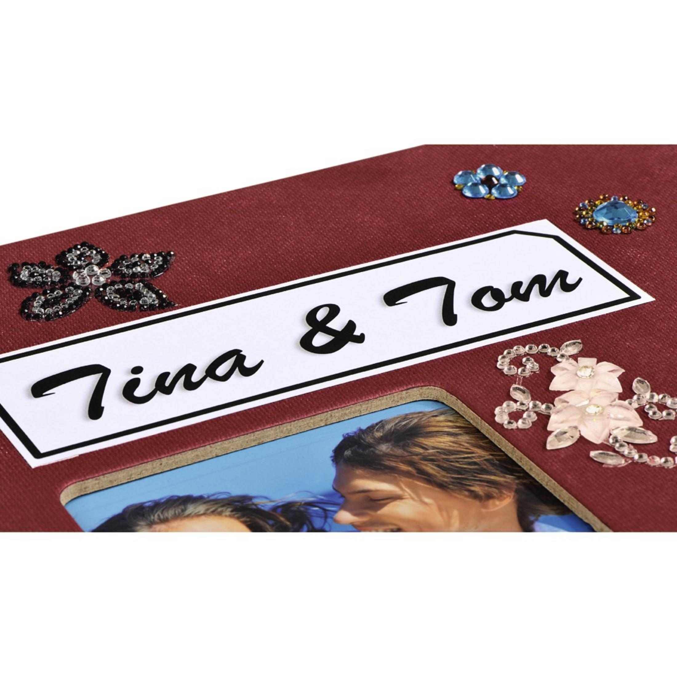 Album fotograficzny z napisem 'Tina & Tom', ozdobiony klejnotami. W środku widoczne zdjęcie.