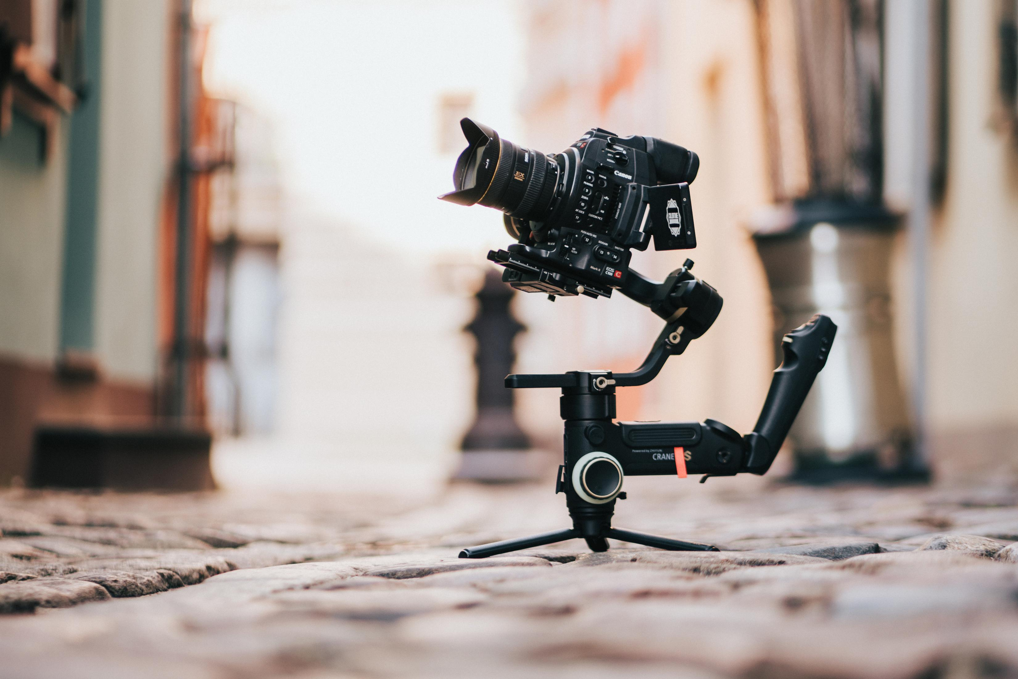 Fotocamera su un gimbal, montata su un treppiede, in una strada acciottolata.