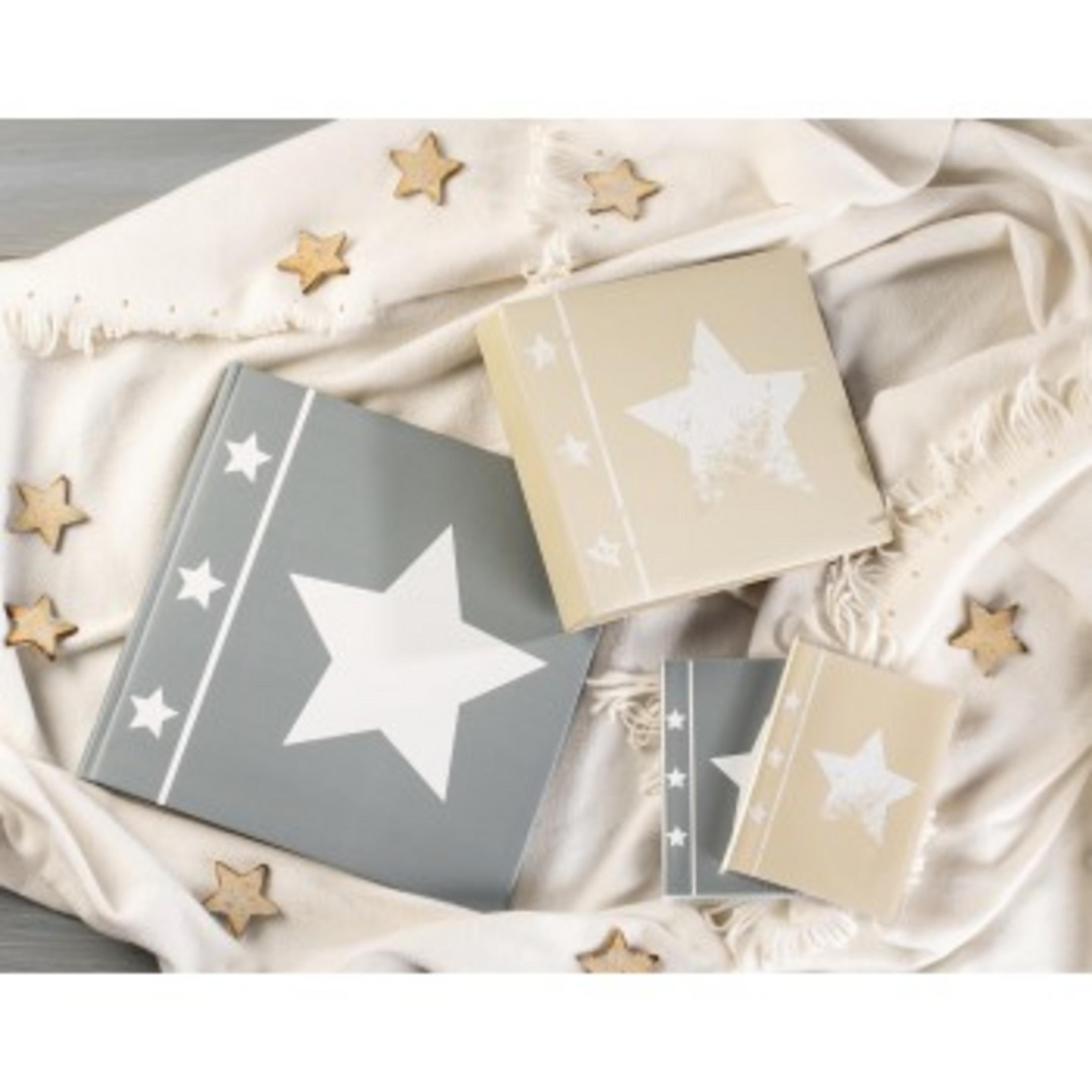 Trzy albumy, szare i kremowe, ozdobione gwiazdami na kremowym kocu.