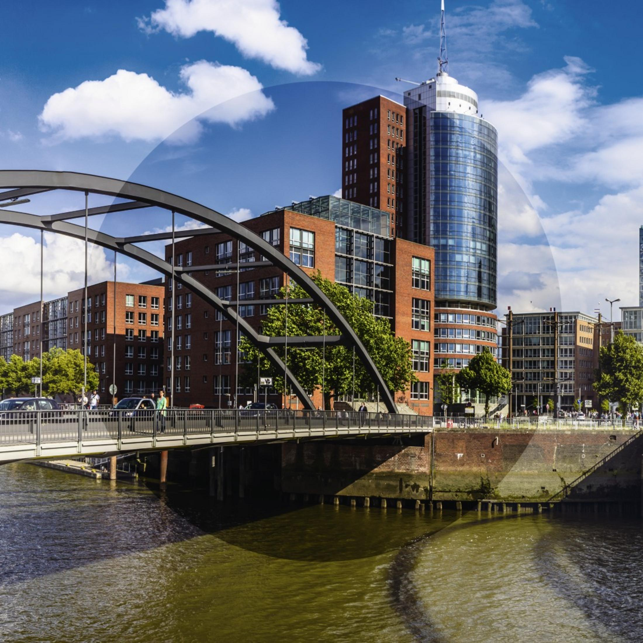 Eine Stadt mit einer Brücke über einen Fluss. Der Himmel ist blau mit Wolken.
