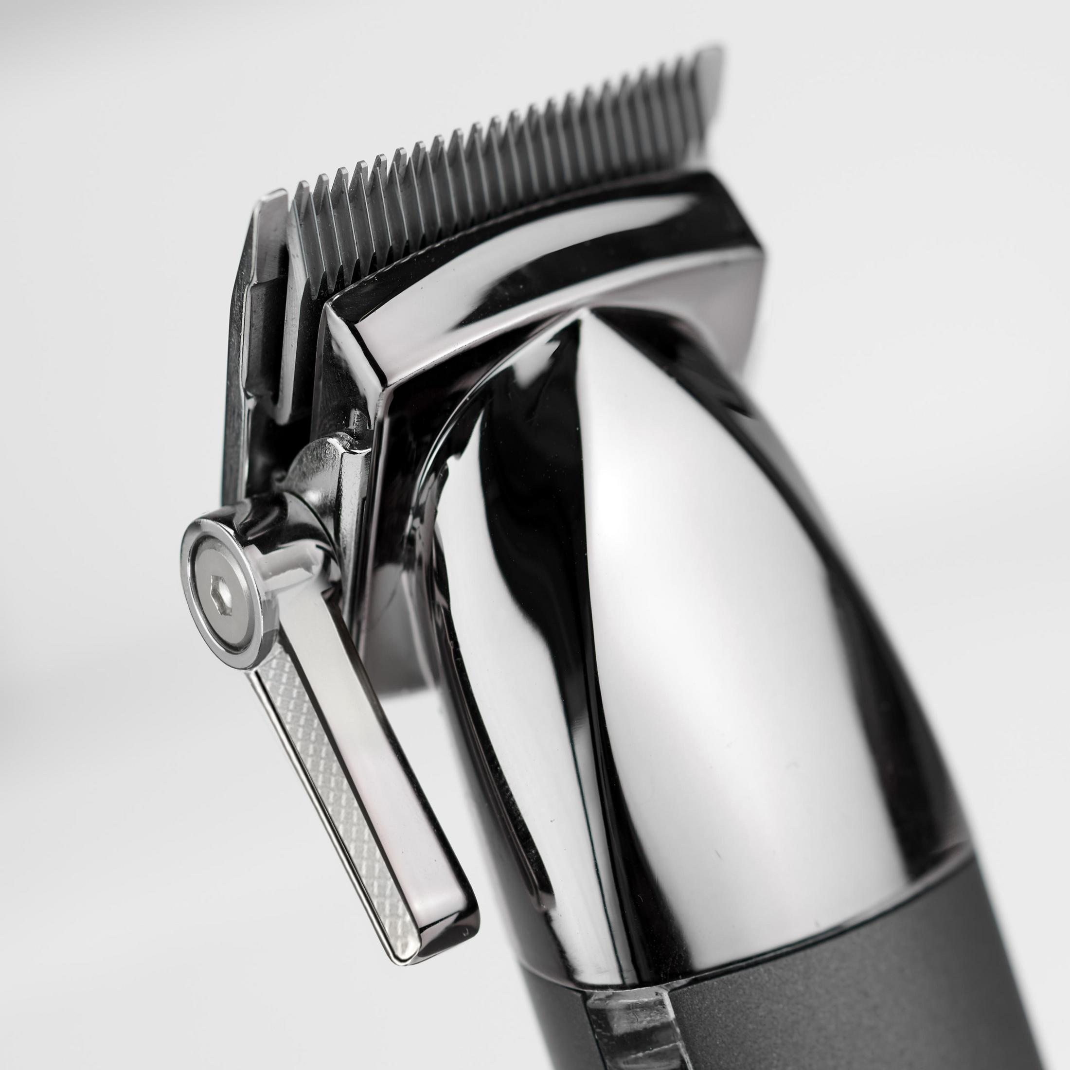 Primer plano de una cortadora de cabello plateada y negra, en ángulo hacia la izquierda. Fondo blanco.