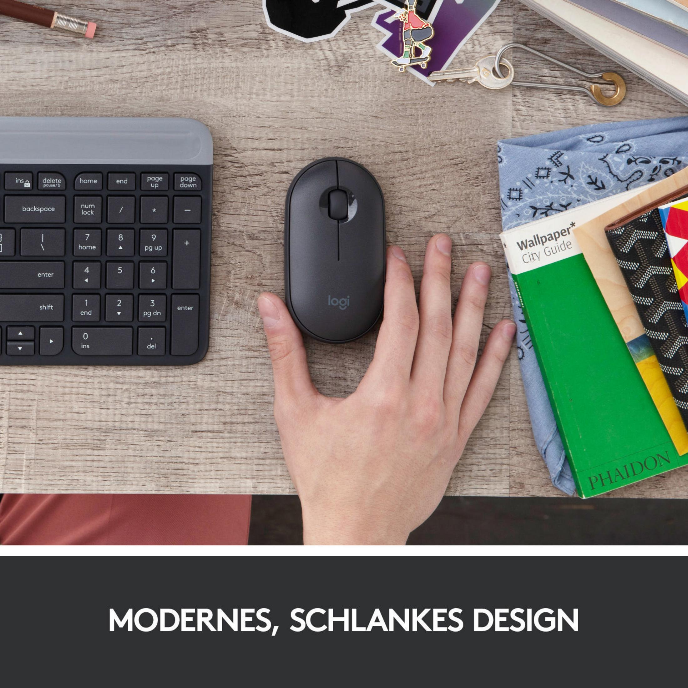 Een hand die een grijze Logitech muis vasthoudt naast een toetsenbord, bureau-artikelen op een houten oppervlak.