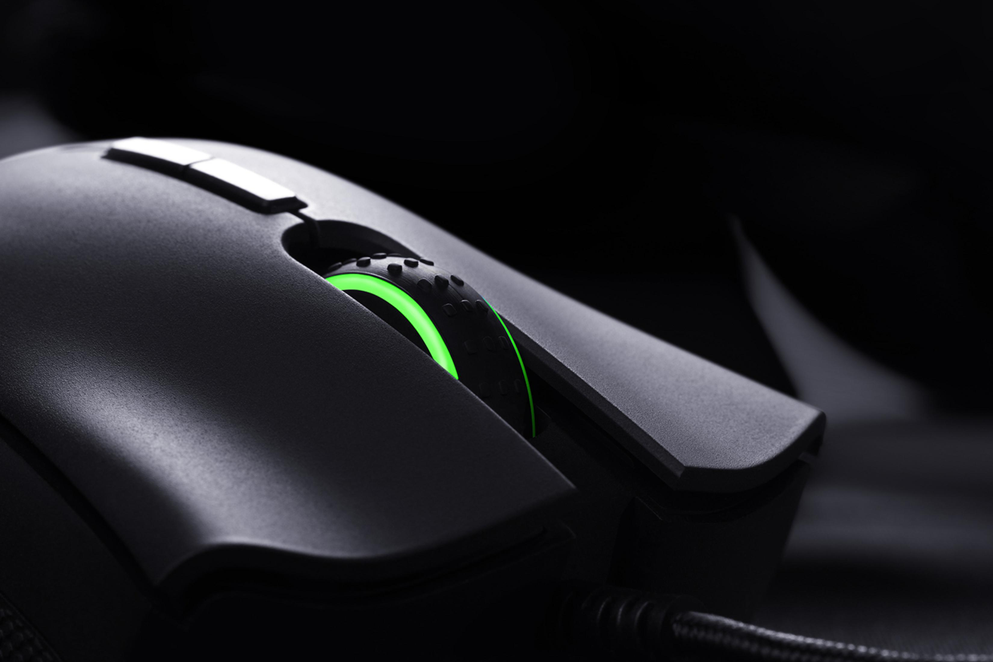 Schwarze Razer Gaming-Maus mit leuchtendem grünen Scrollrad, auf dunkler Oberfläche.