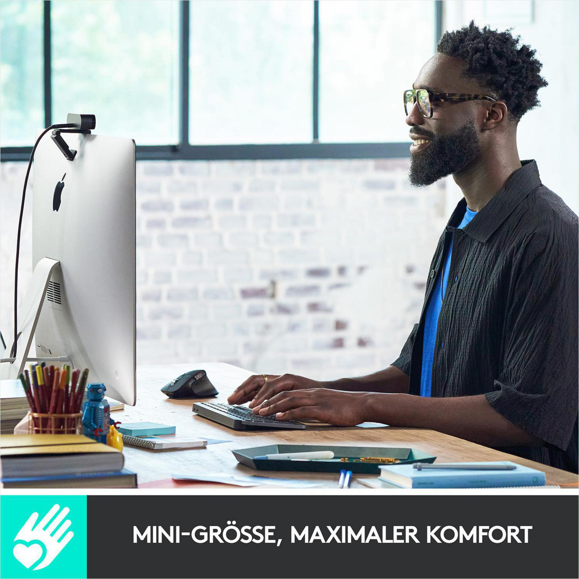 Mężczyzna korzystający z komputera z monitorem, klawiaturą i myszą, w biurze.