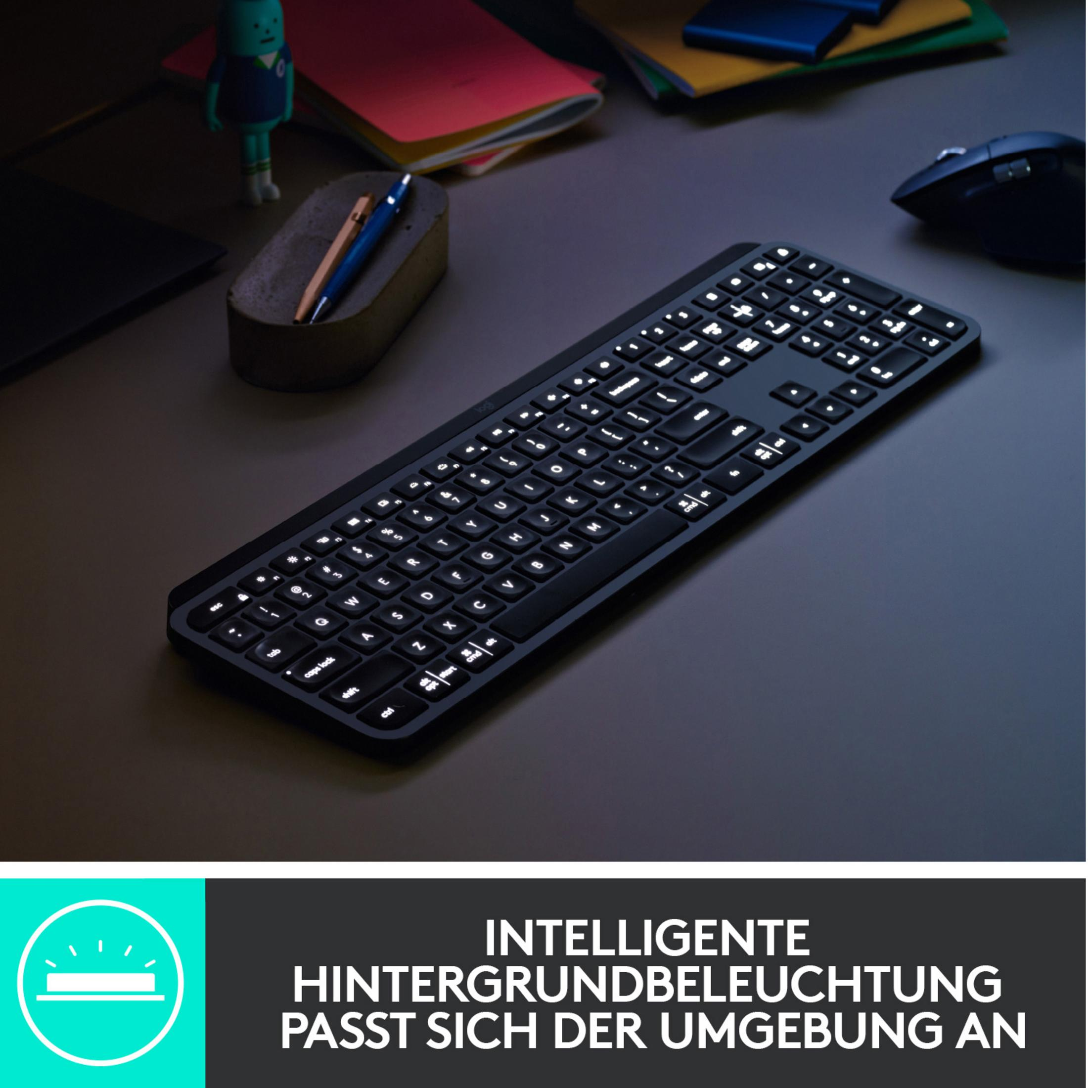 Schwarze Tastatur mit weiß beleuchteten Tasten auf einem dunklen Schreibtisch. Maus und andere Gegenstände sind sichtbar.