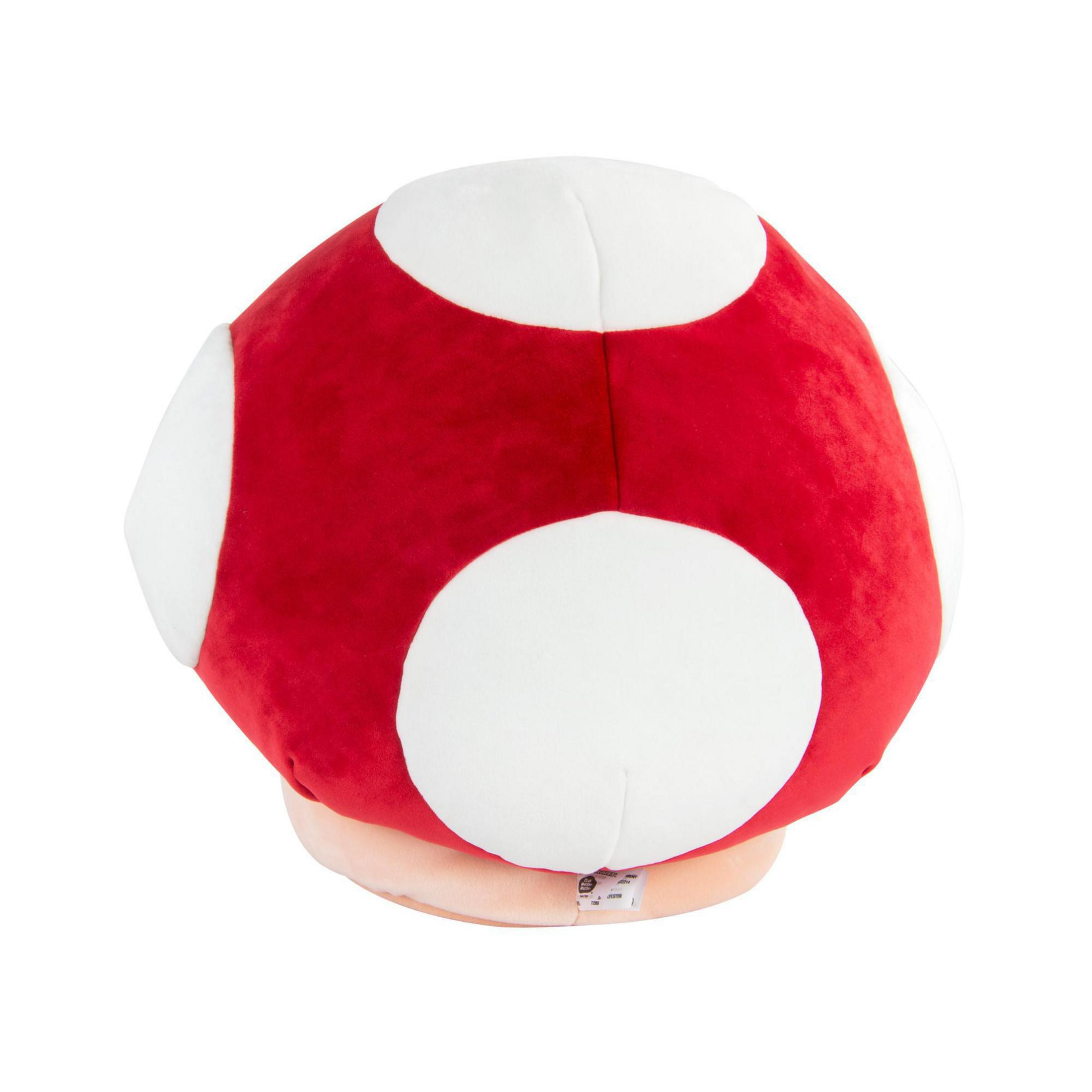 Un grande giocattolo a forma di fungo rosso con macchie bianche. Ha una base marrone chiaro. Sfondo bianco.