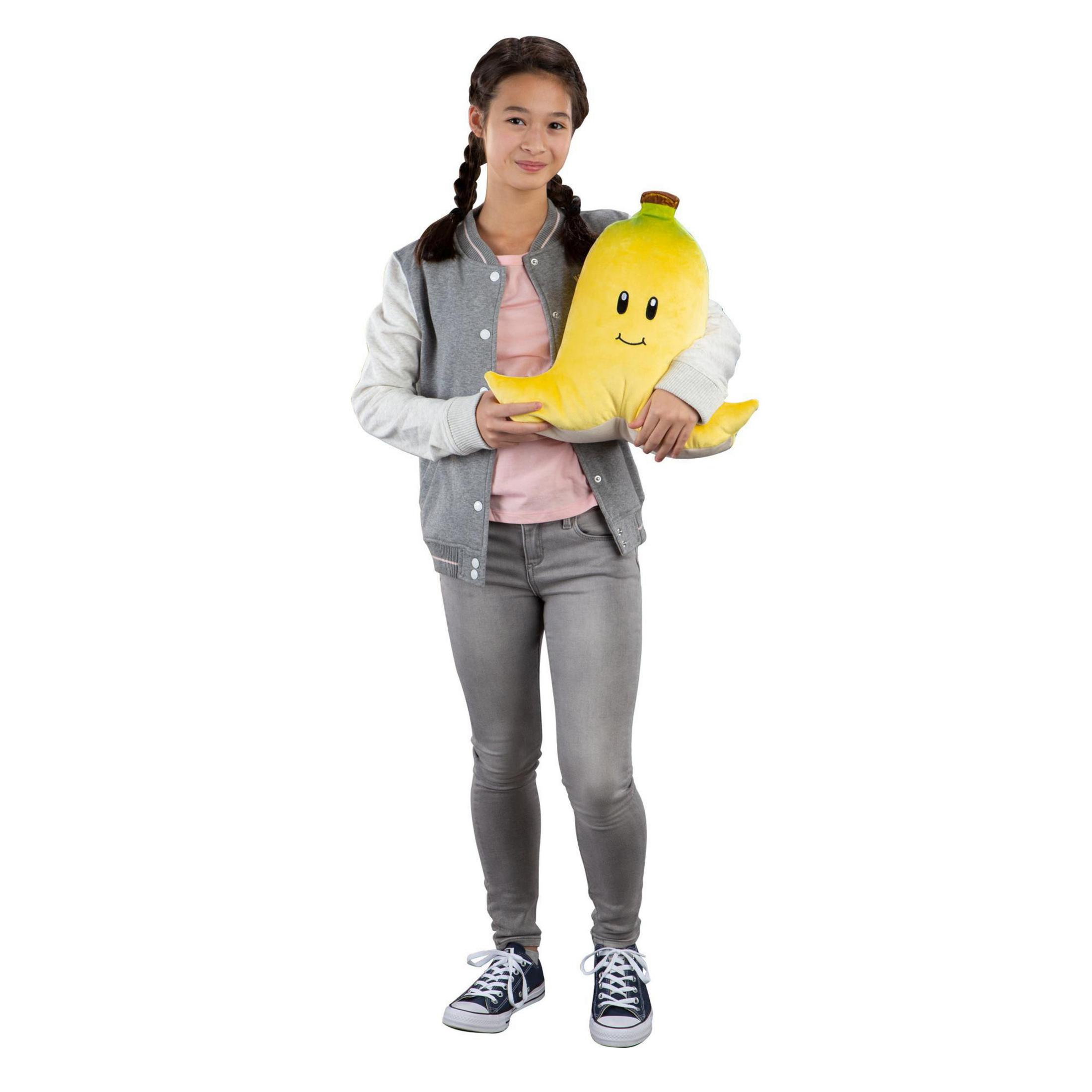 Jeune fille tenant une banane en peluche jaune. Elle porte une veste grise, une chemise rose et un jean.