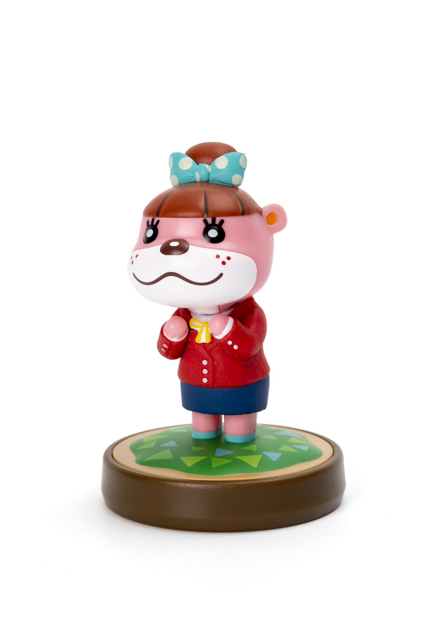 Eine kleine Figur eines rosa Bärencharakters. Es trägt einen roten Mantel und einen blauen Rock. Es hat eine grüne Basis.