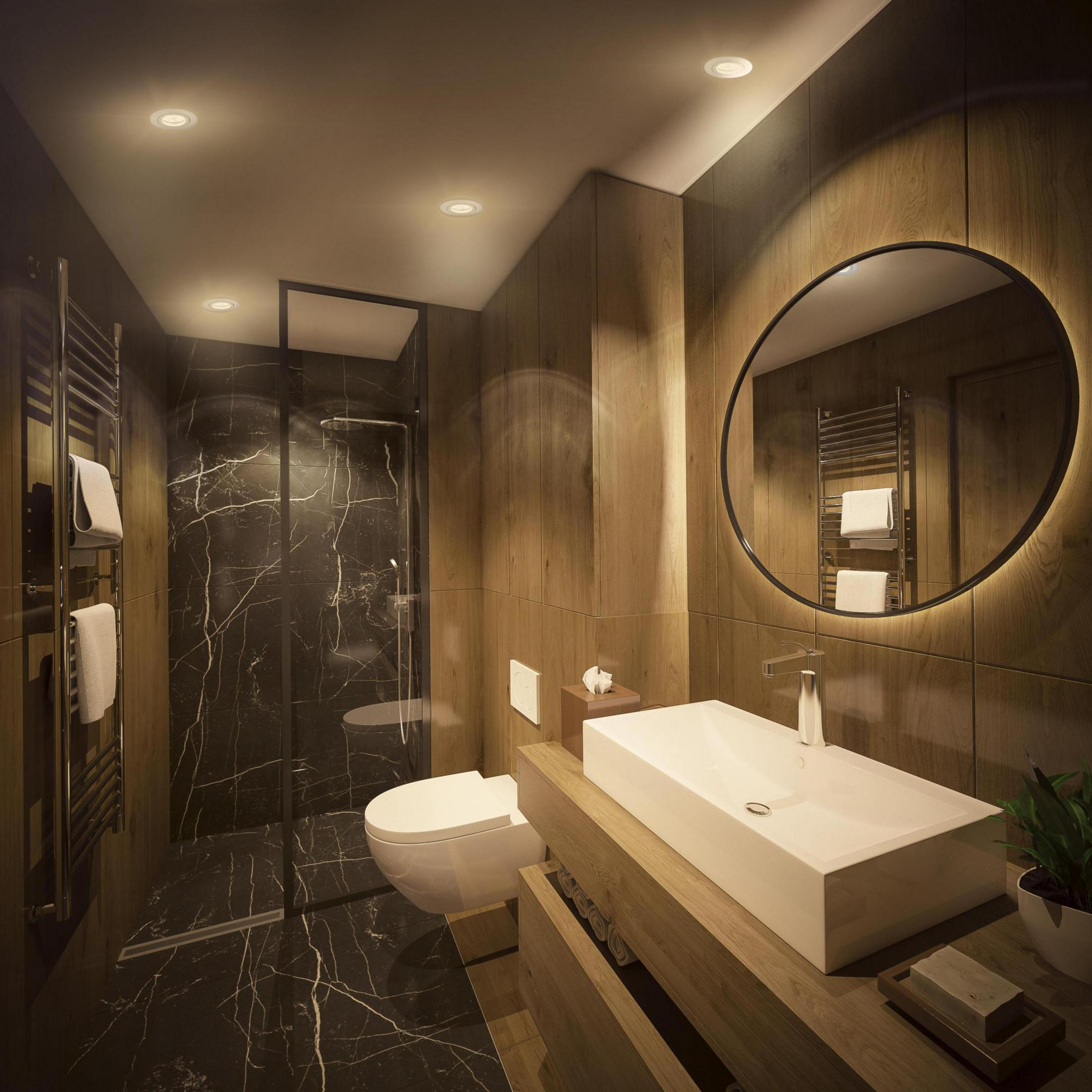 Nowoczesna łazienka z marmurowymi ścianami, dużym lustrem i drewnianymi akcentami. Posiada białą umywalkę i toaletę.