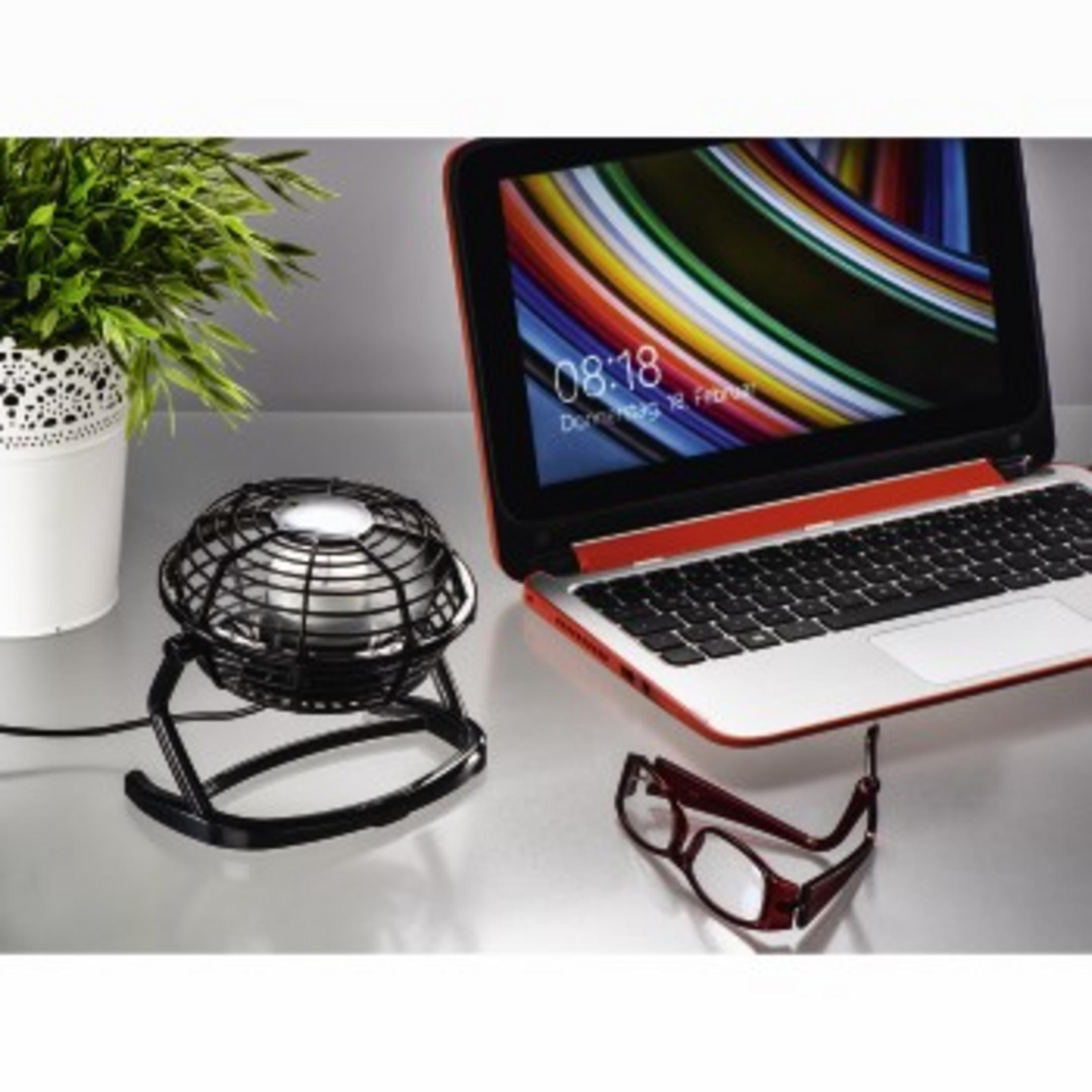 Ein kleiner Ventilator, ein Laptop mit 08:18 und eine Brille auf dem Tisch.