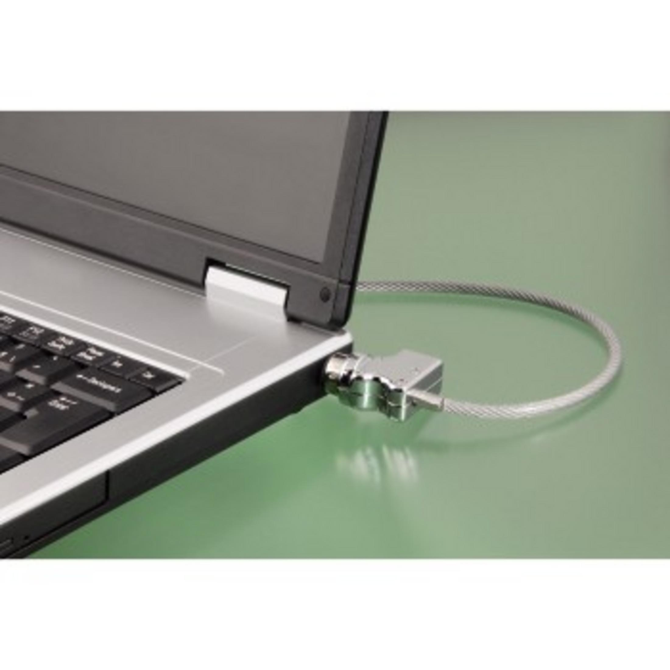 Laptop mit silbernem Kabel-Schloss gesichert, auf grüner Oberfläche.