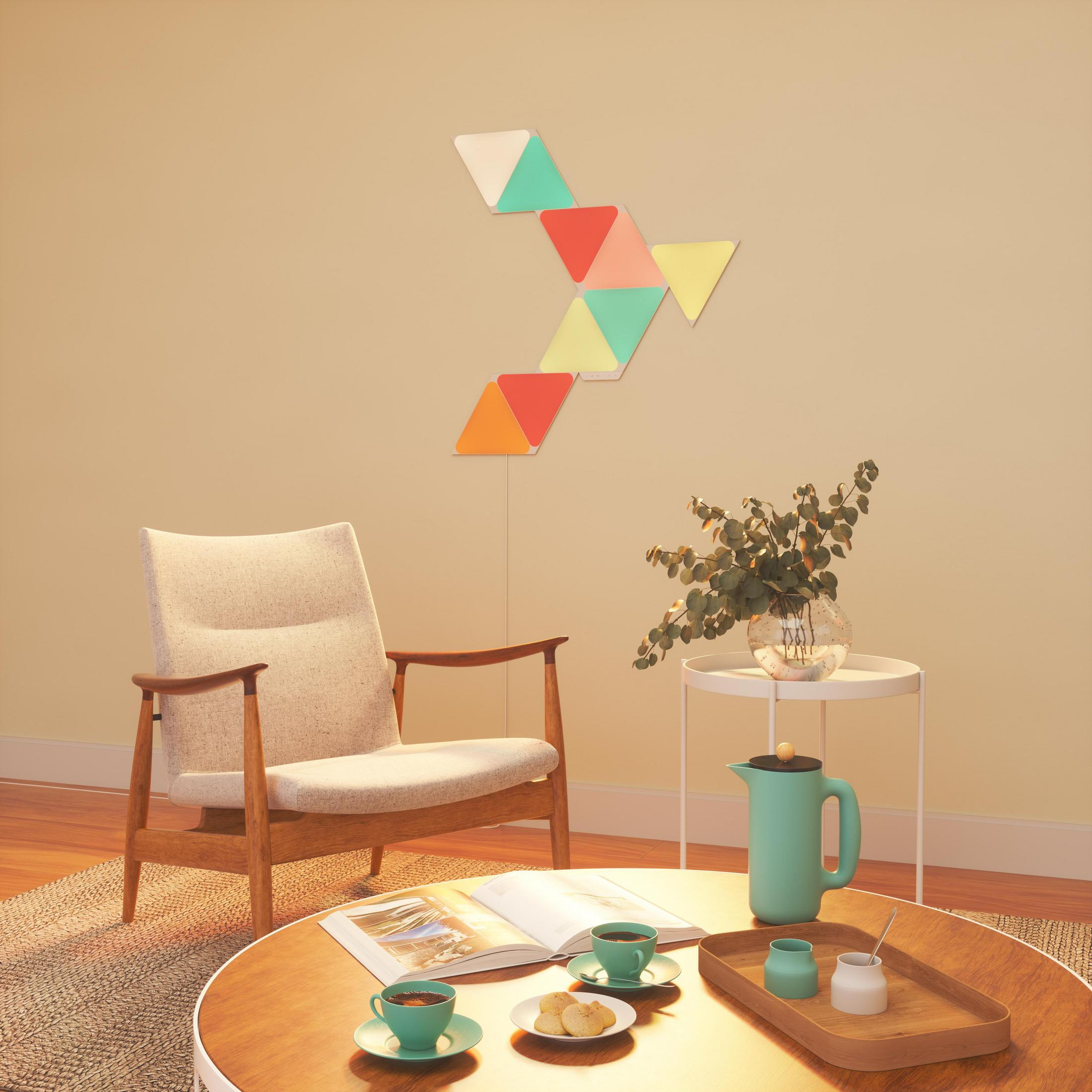 Eine moderne Wohnzimmereinrichtung mit Stuhl, Tisch und farbigen Wandleuchten. Ein Kaffee-Setup ist vorhanden.