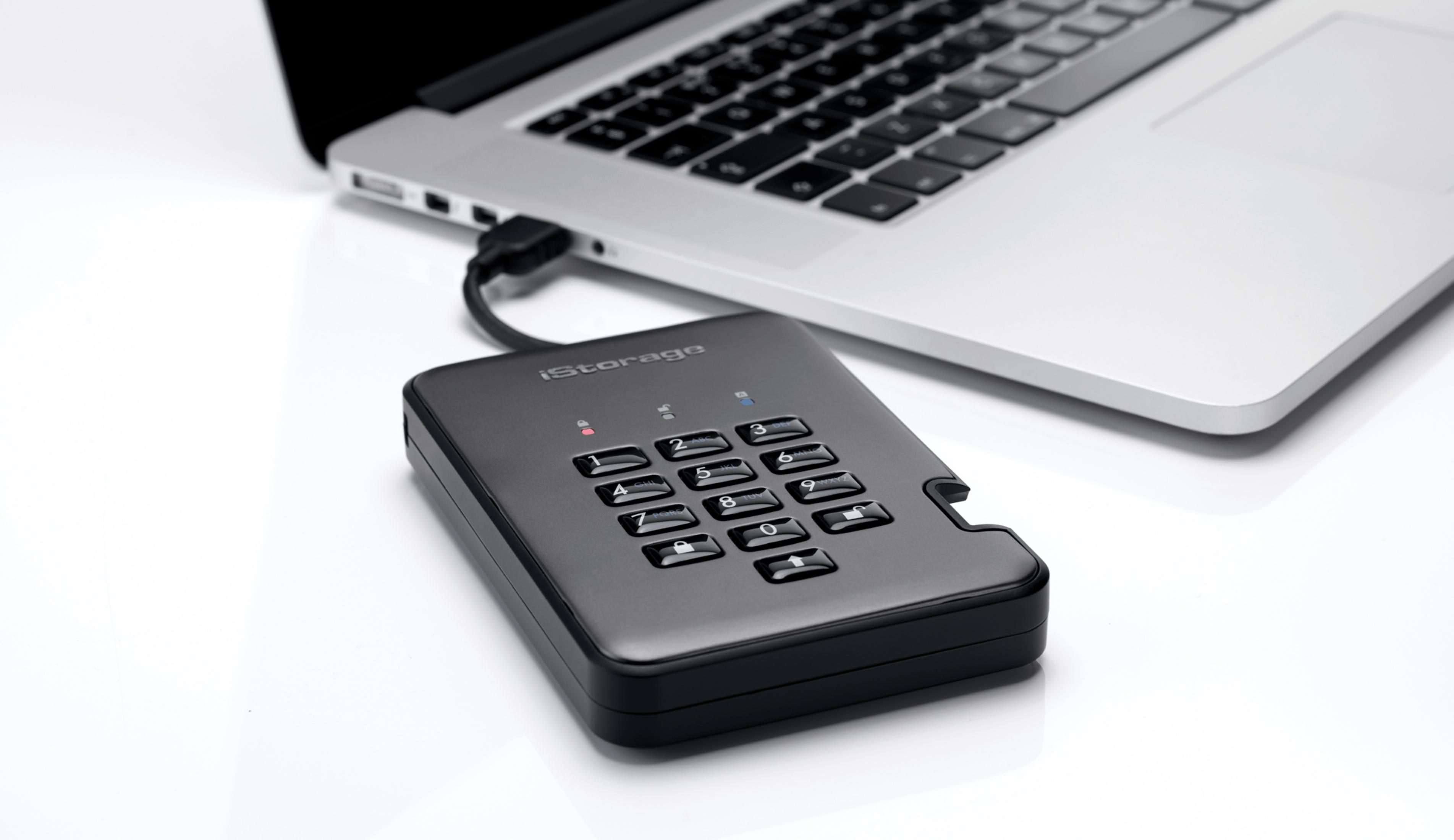 Un disco duro externo negro con teclado conectado a una laptop.